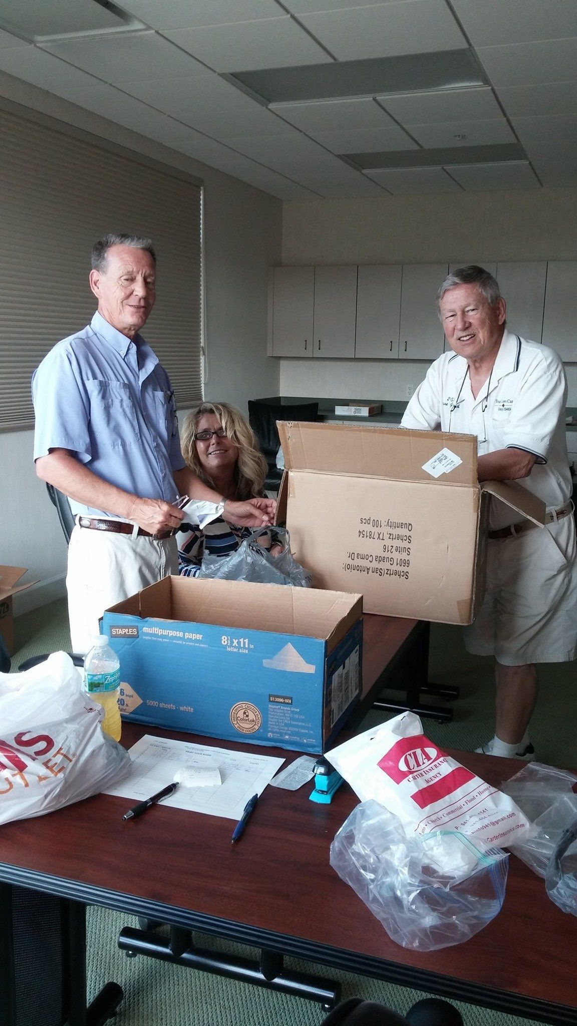 Three men are standing around a table with a box on it that says ' a ' on it