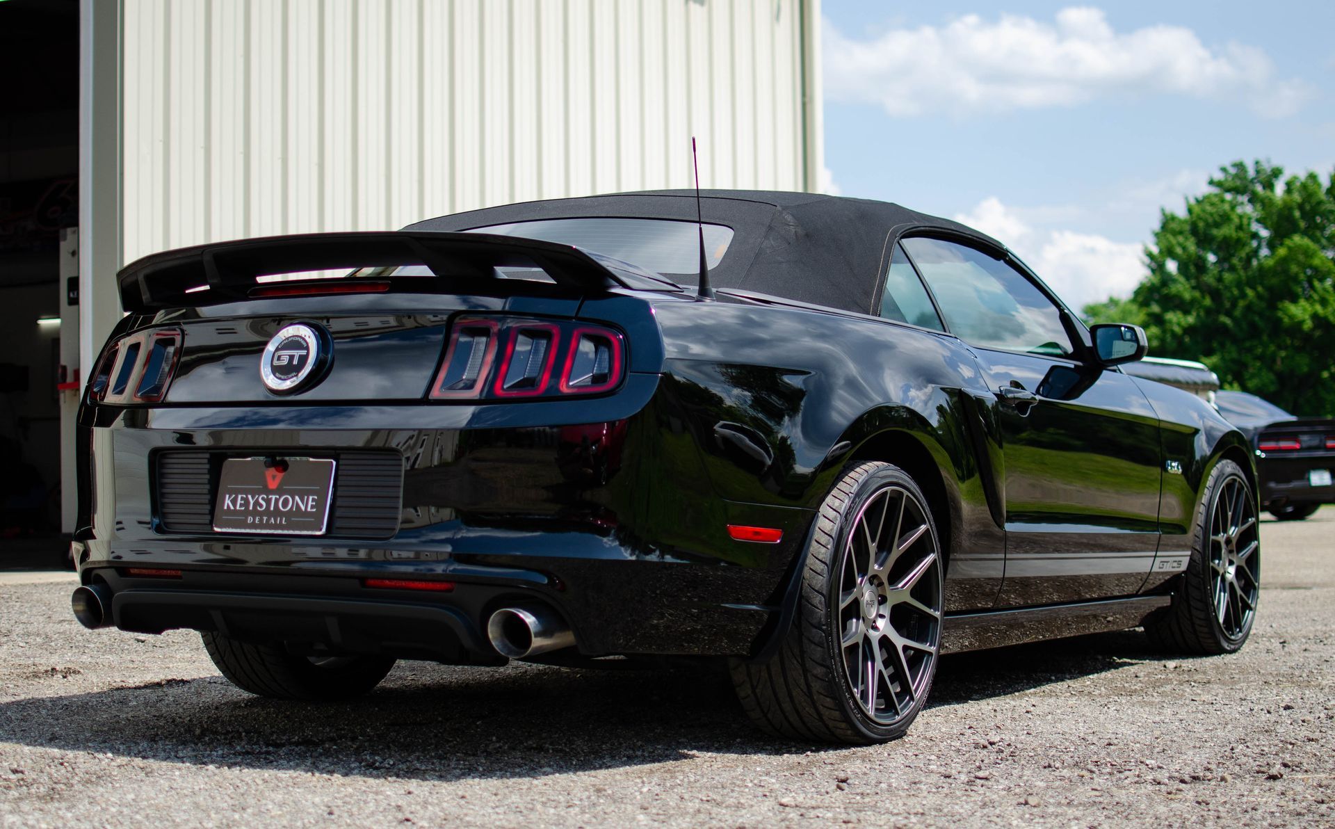 Black convertible Ford Mustang parked outside a building.