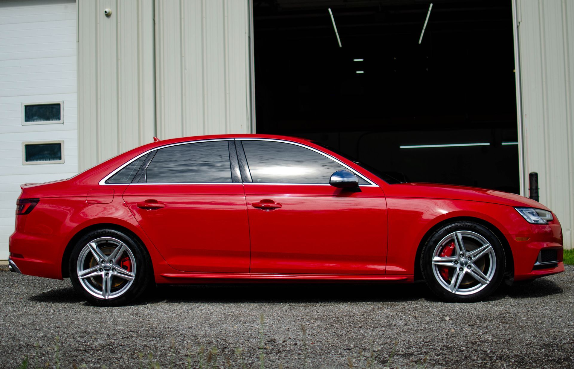 Red Audi sedan parked in front of a building with an open black door.
