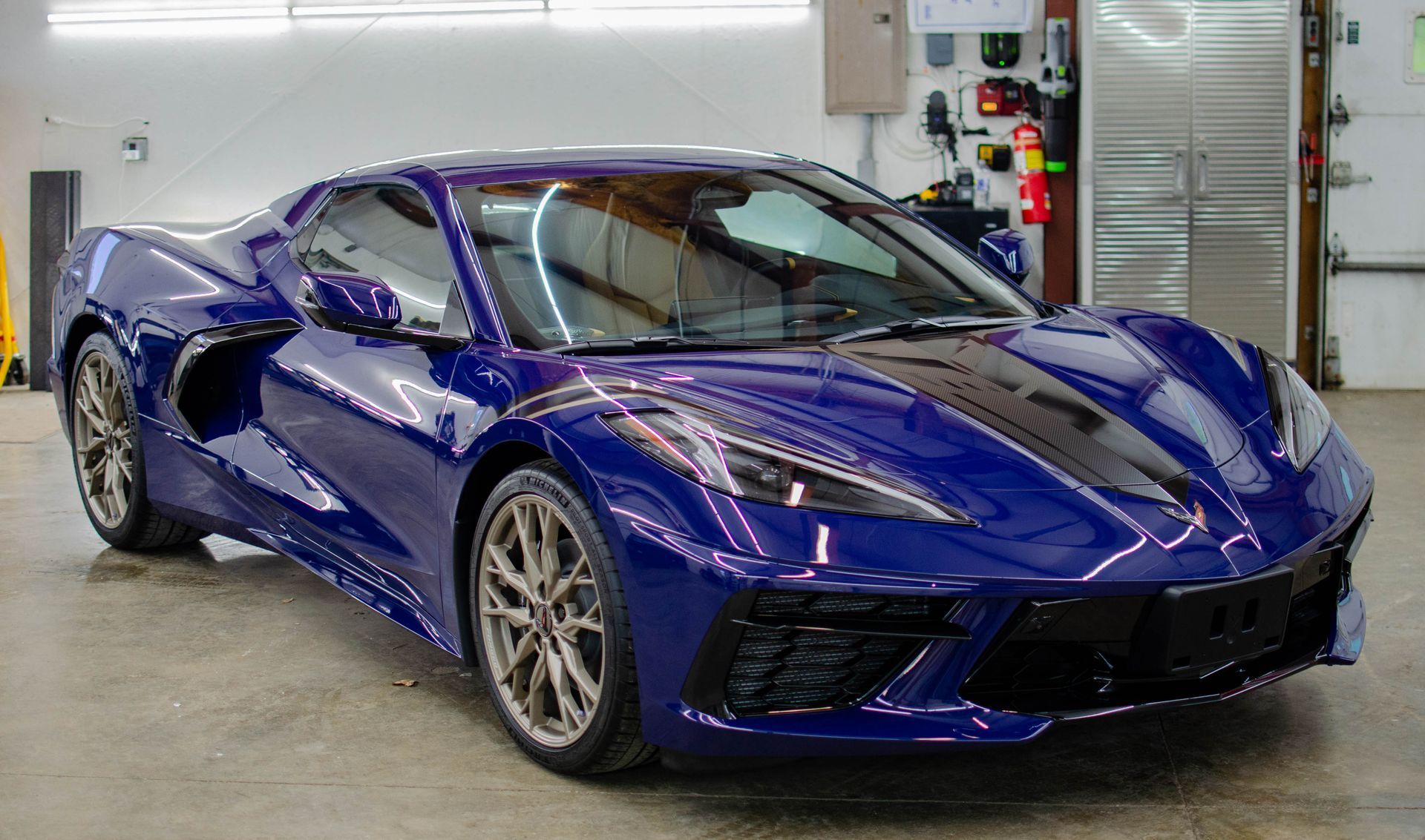Blue Chevrolet Corvette sports car in a garage with a black hood.