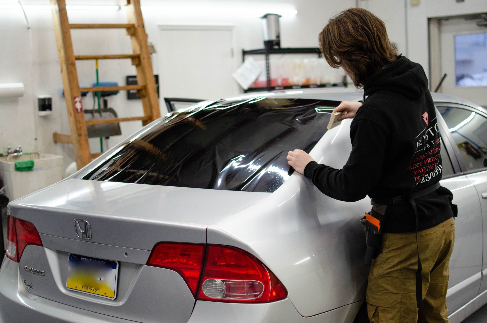 Smiling person in black hoodie and cap with red graffiti background.