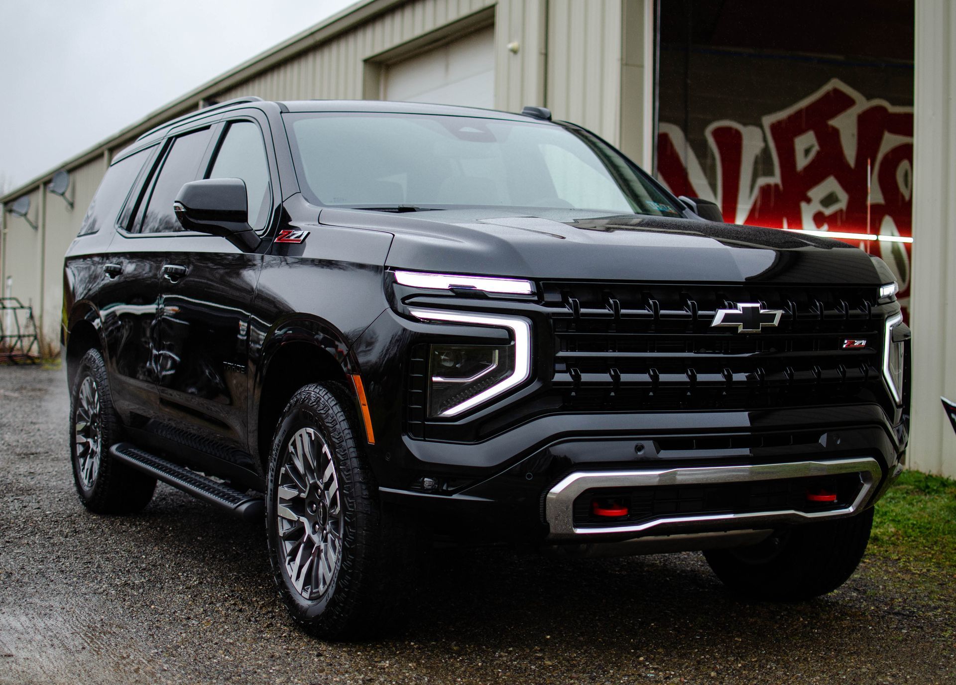 Black Chevrolet Tahoe SUV parked in front of a garage with graffiti.