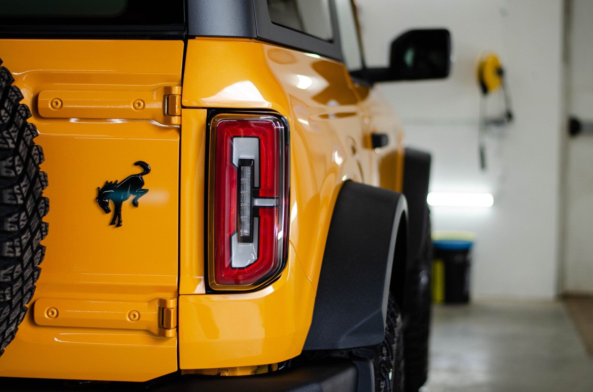 Yellow Ford Bronco rear with black accents and spare tire.