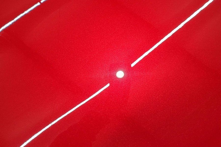 a close up of a red car with a white line on it .