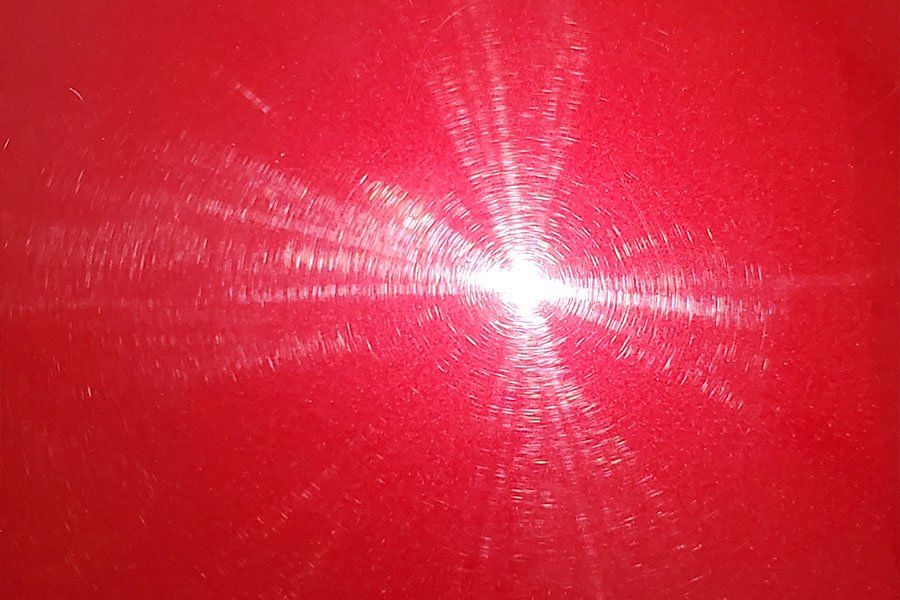 a close up of a red surface with a light shining through it .