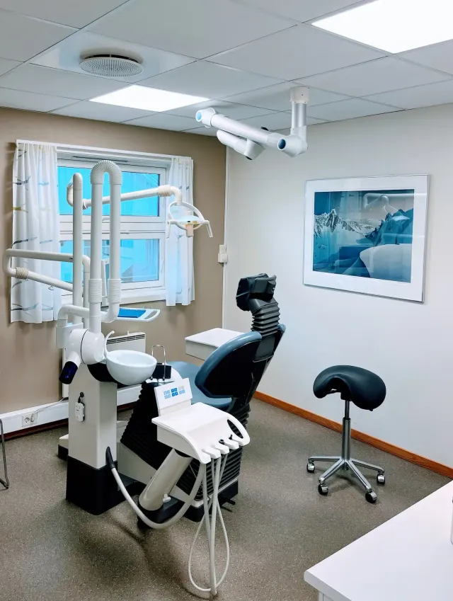 Tannlegekontorinteriør med stol, lys, verktøy og et vindu.