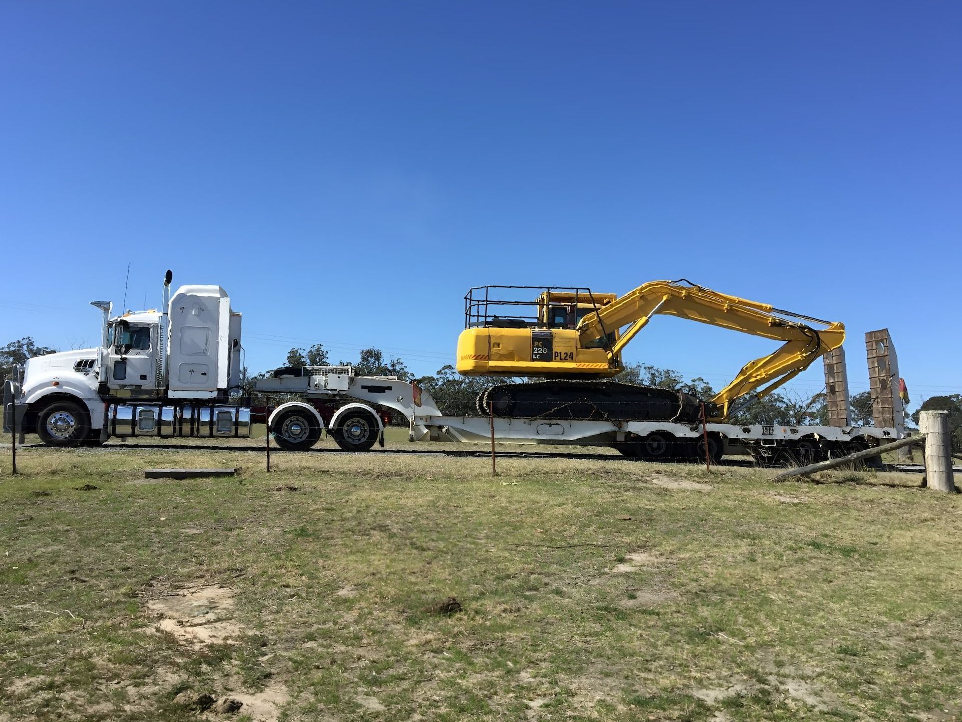 A Yellow Excavator is being transported by a large semi truck — Total Vegetation Management in Braemar, NSW