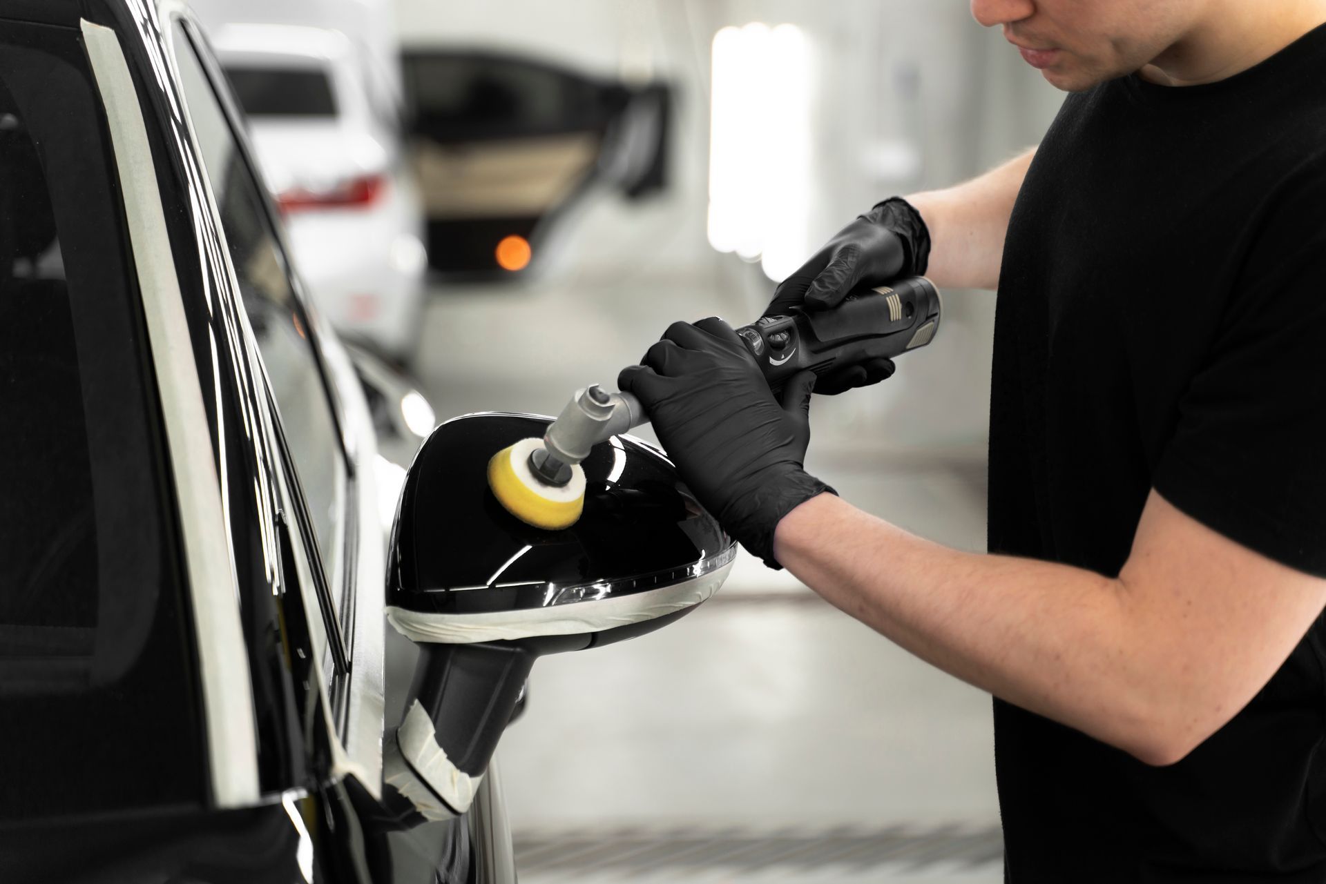 A man is polishing the side mirror of a car.