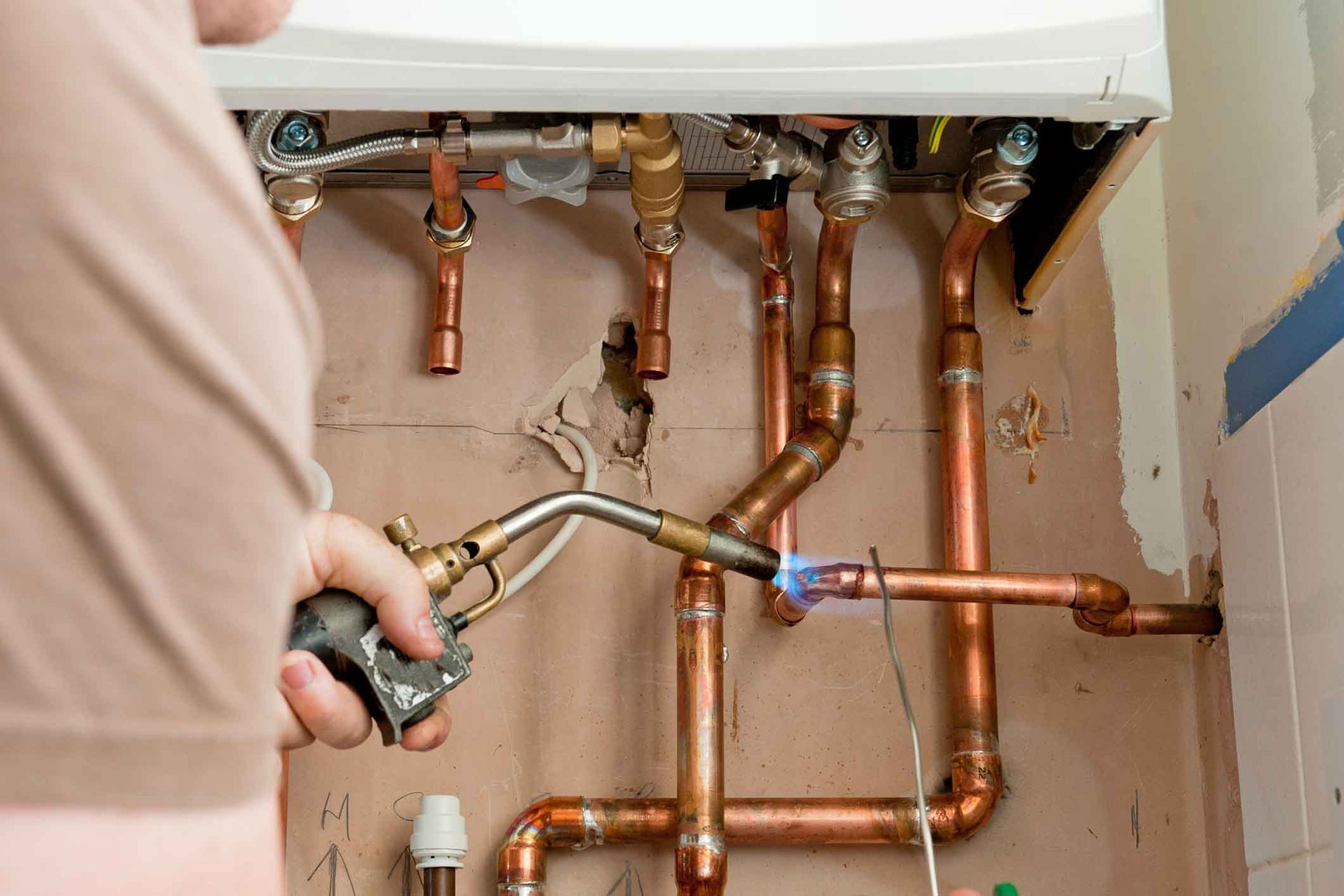 A person is using a torch to fix copper pipes.