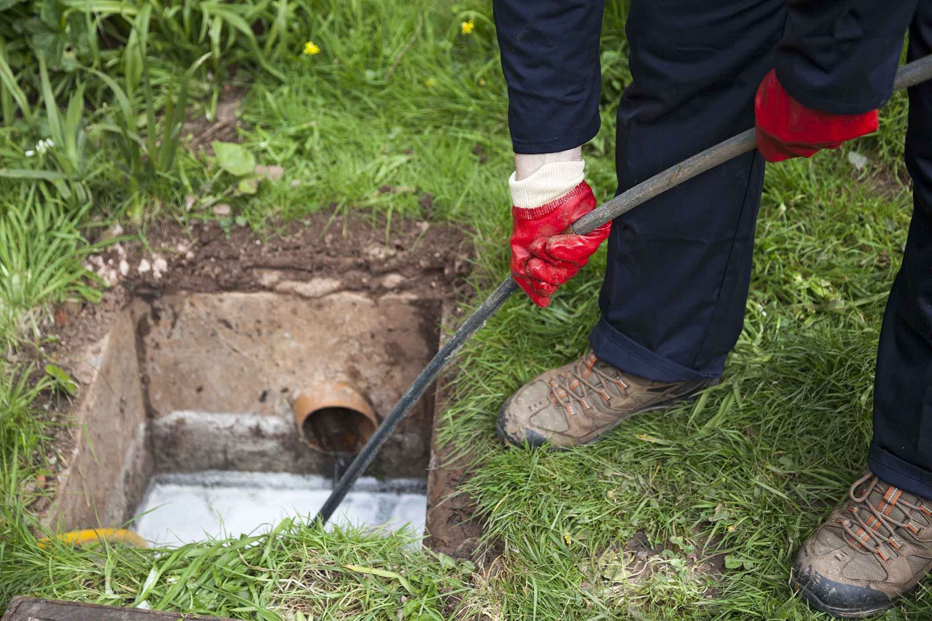 A person is cleaning a septic tank with a hose.