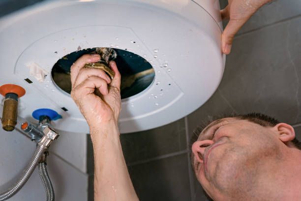 A man is fixing a water heater in a bathroom.