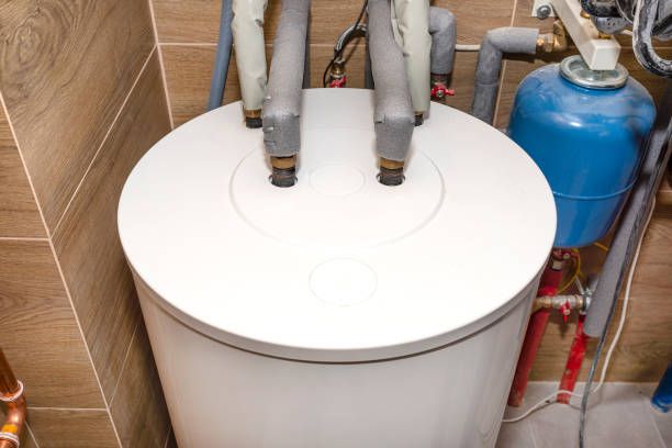 A white water heater is sitting in a room next to a blue tank.