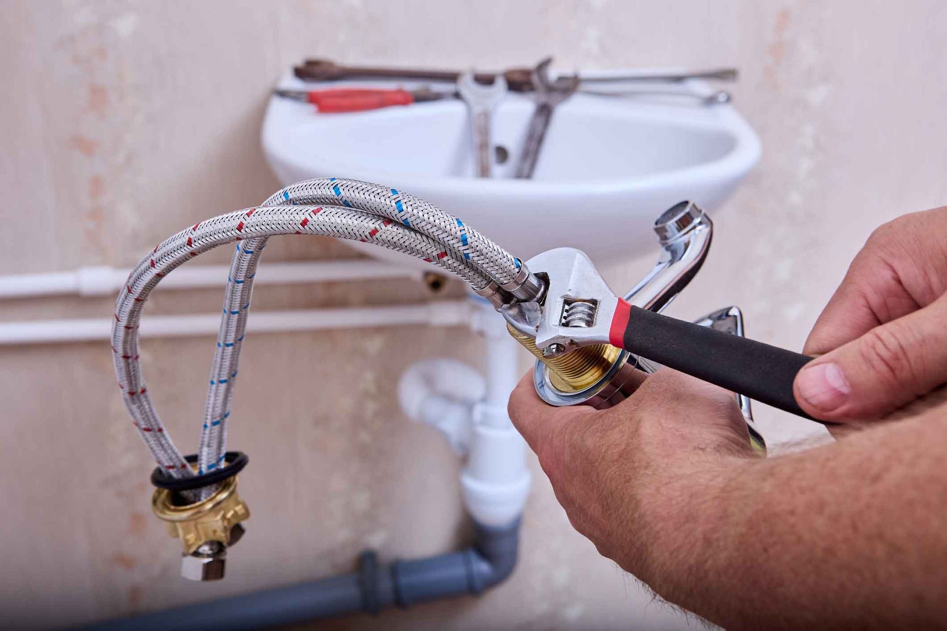 A plumber is fixing a sink faucet with a wrench.