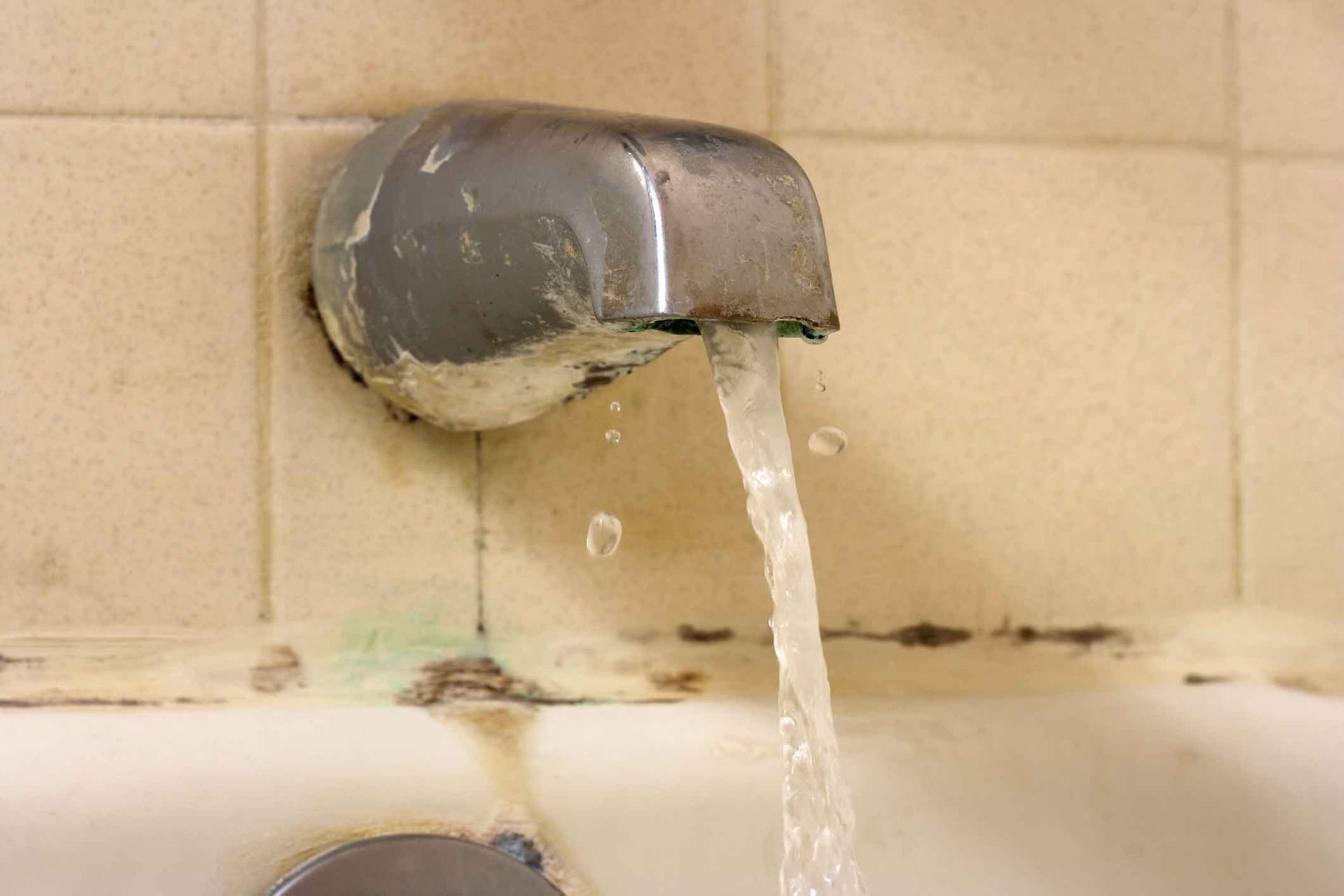 Water is pouring out of a faucet into a bathtub.