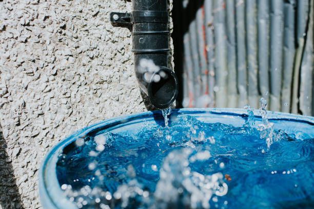 Water is coming out of a pipe into a blue bucket.