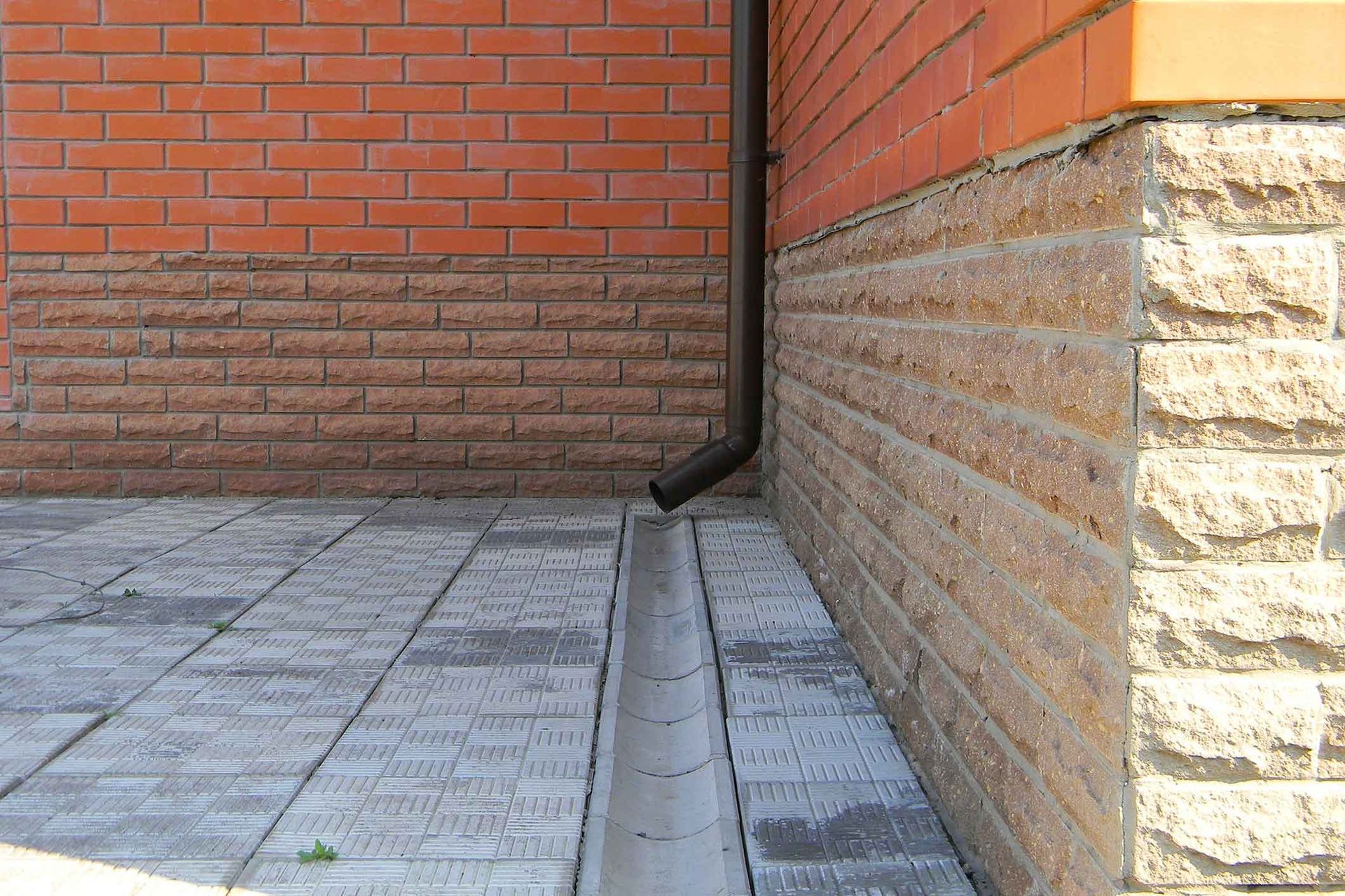 A brick wall with a drain pipe on the side of it.