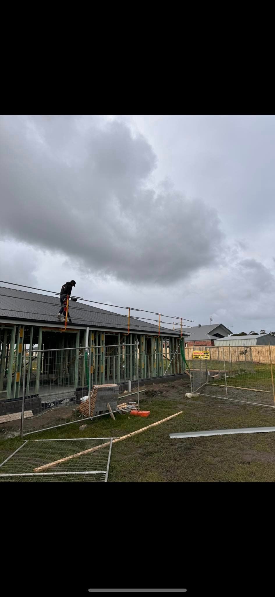 A man is standing on the roof of a building under construction.