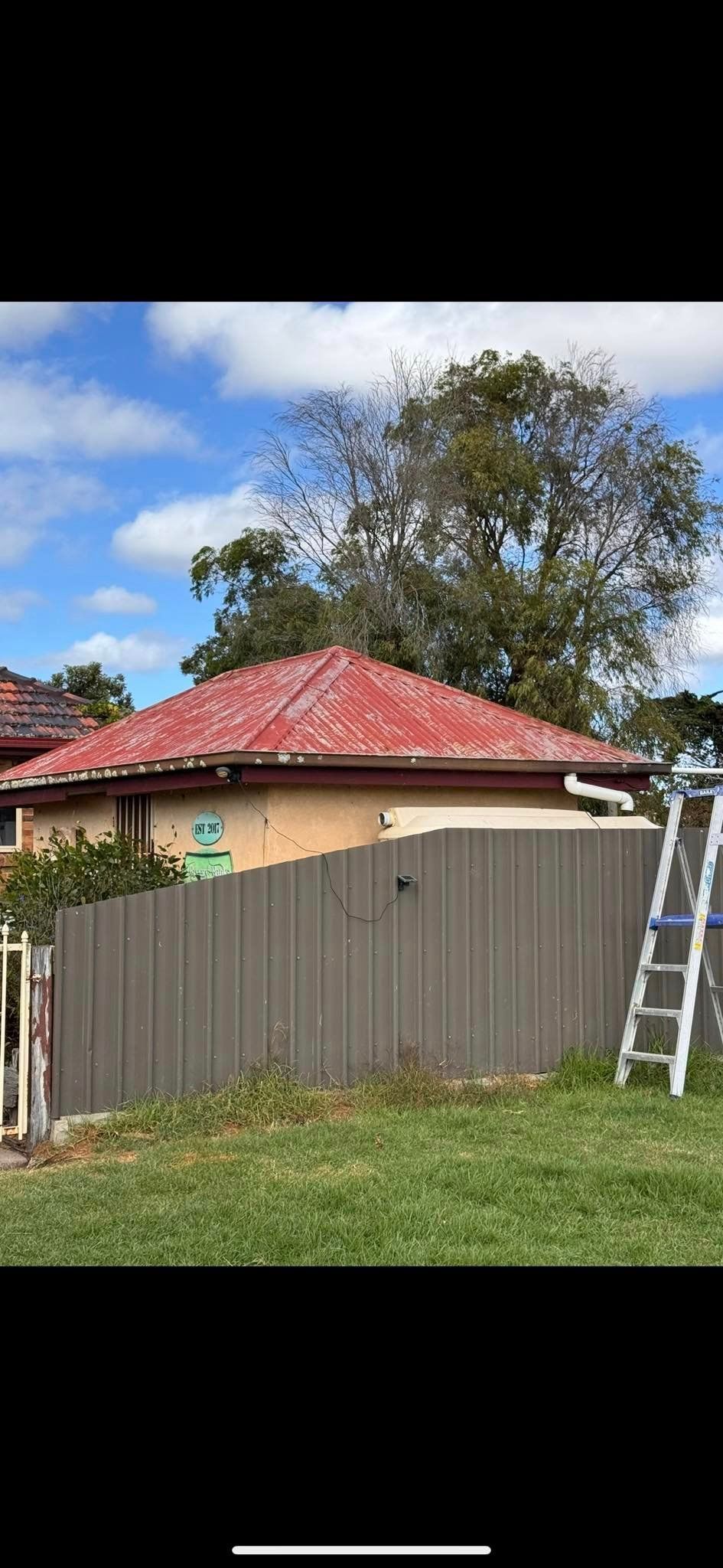 A house with a red roof and a ladder in front of it.