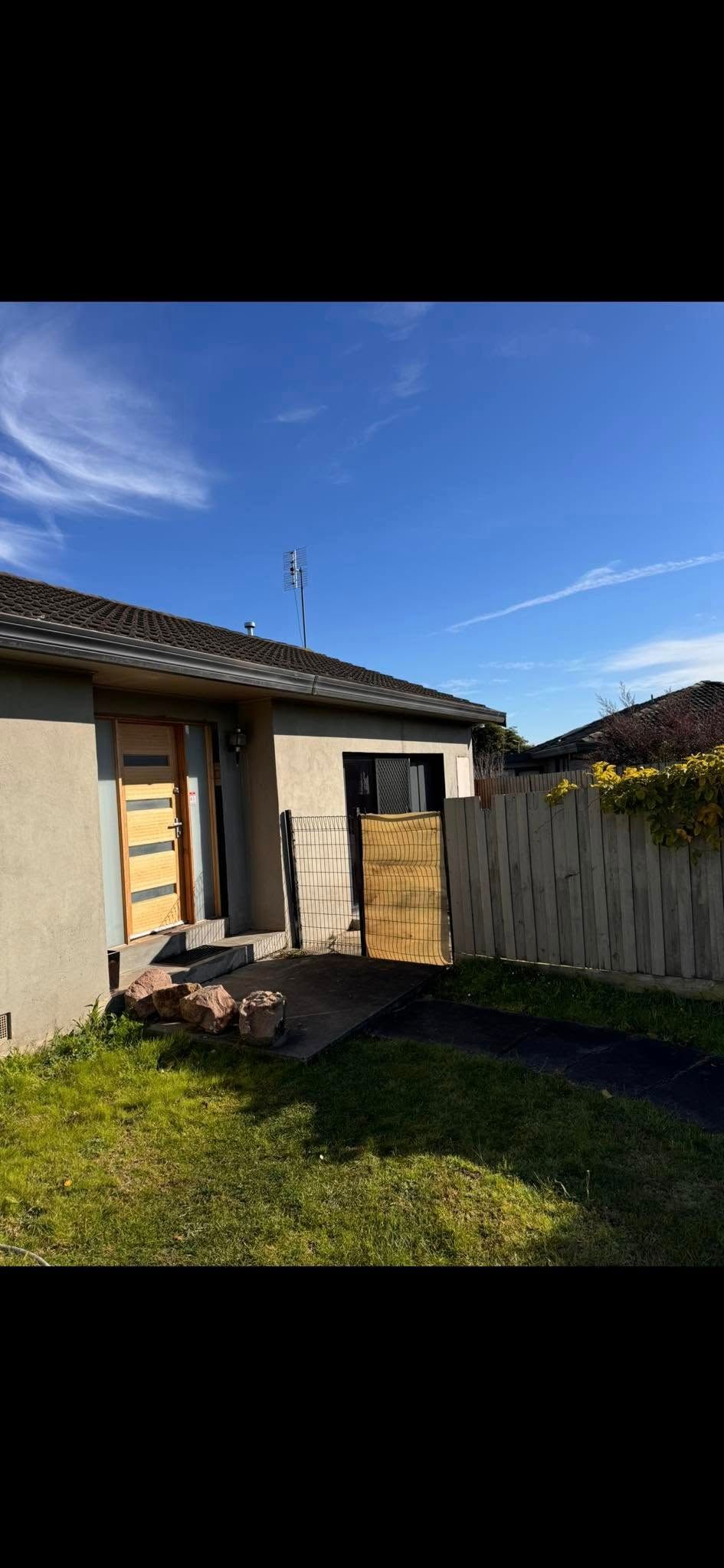 A house with a fence in front of it and a blue sky in the background.