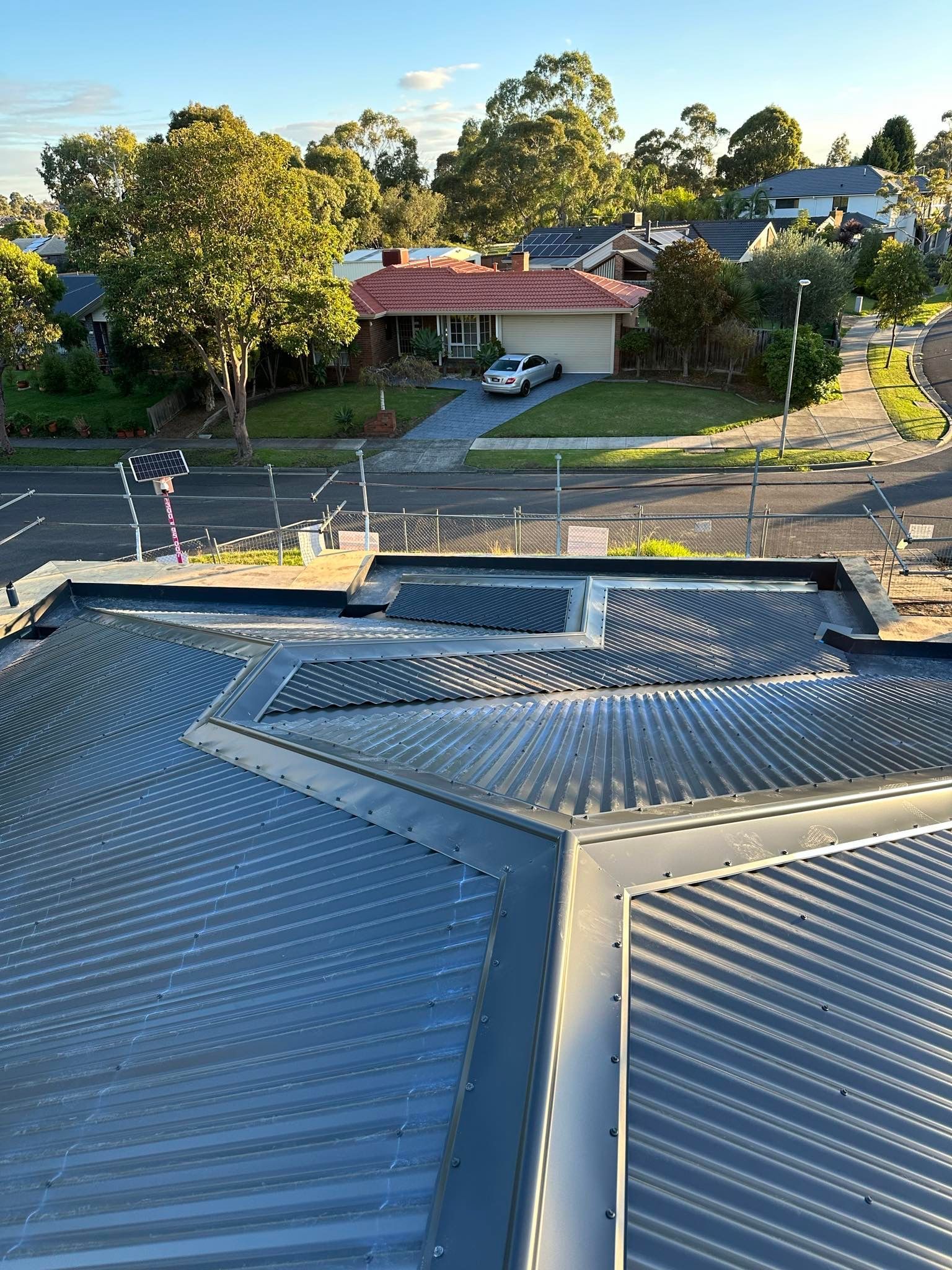 A house with a fence around it and a cloudy sky in the background.