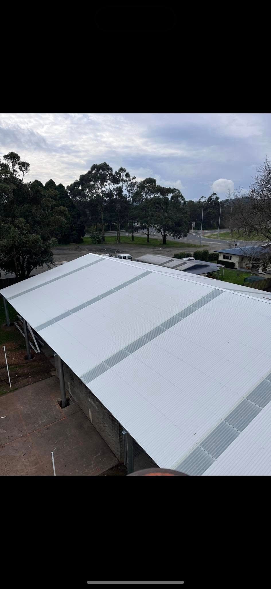 A white tent is sitting on top of a building with trees in the background.