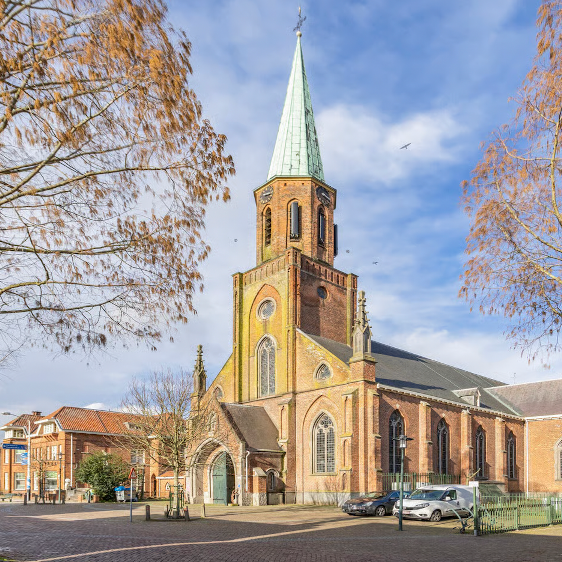 Luchtfoto van een historisch Europees stadje met rode pannendaken, omgeven door groene velden en een gracht.