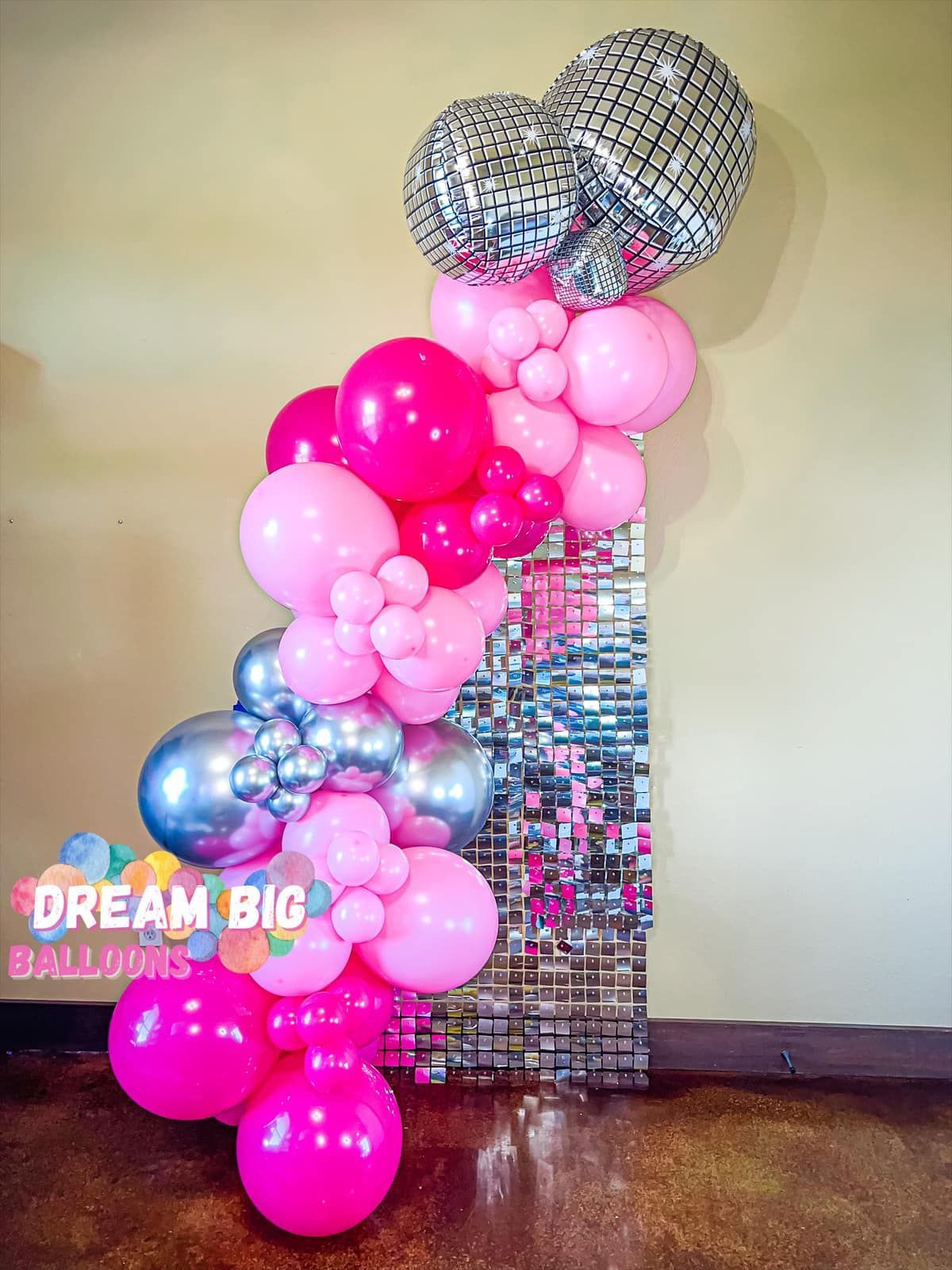 a bunch of pink and silver balloons are sitting on a table