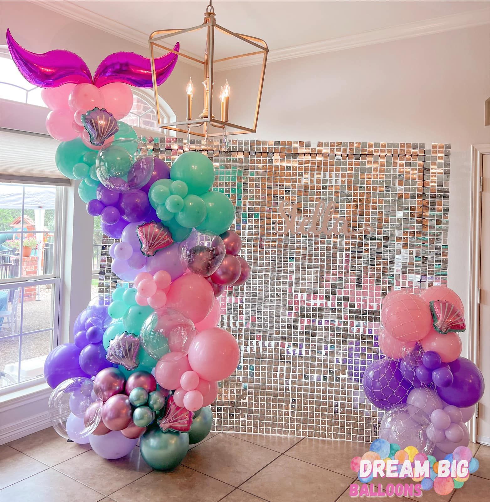 a room filled with balloons and a mermaid tail balloon