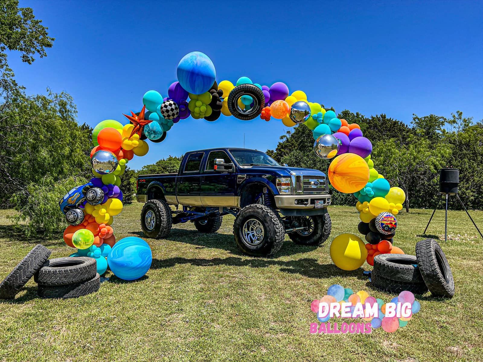 a truck is parked in front of a colorful balloon arch
