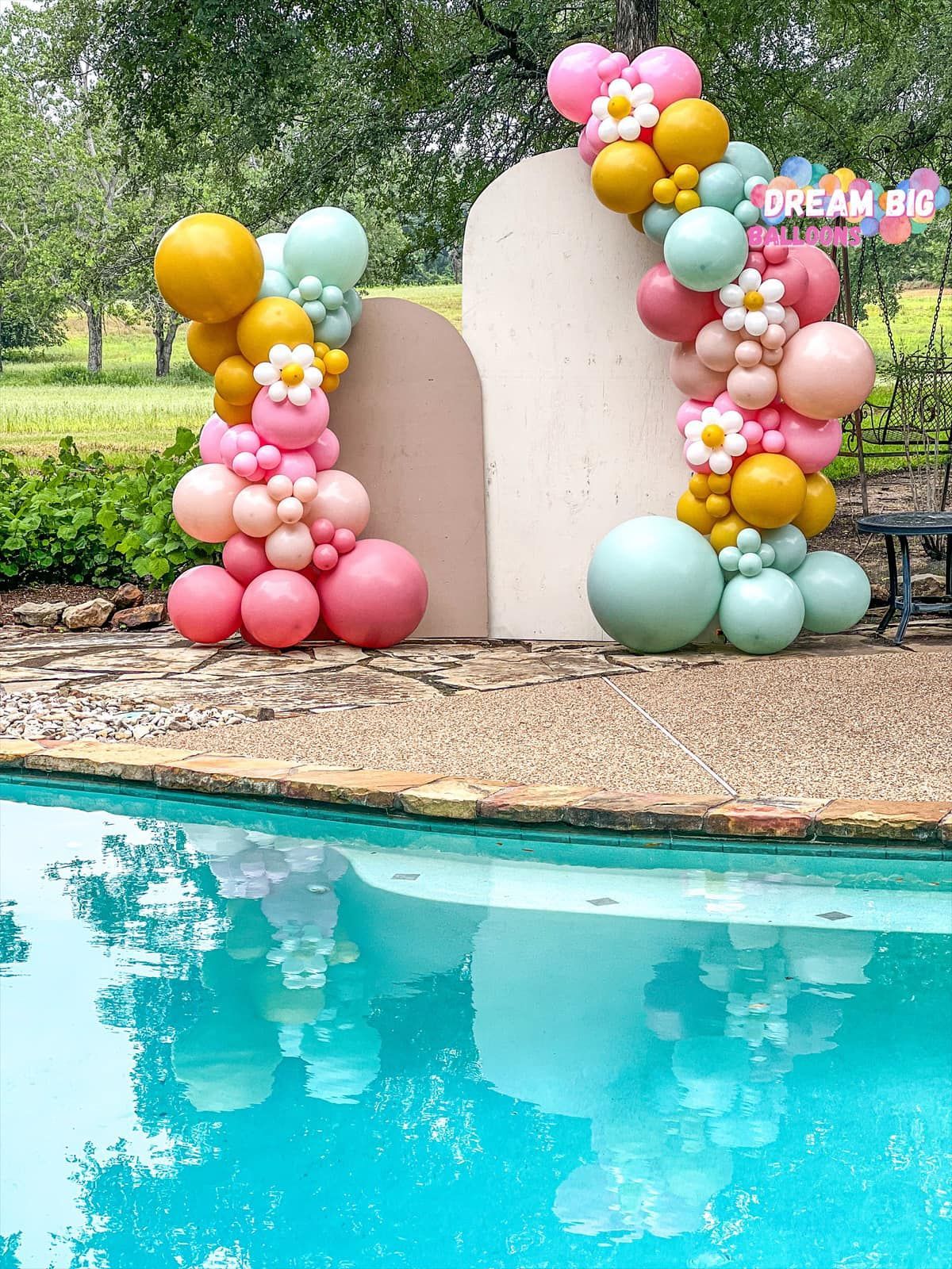a bunch of balloons are sitting next to a pool