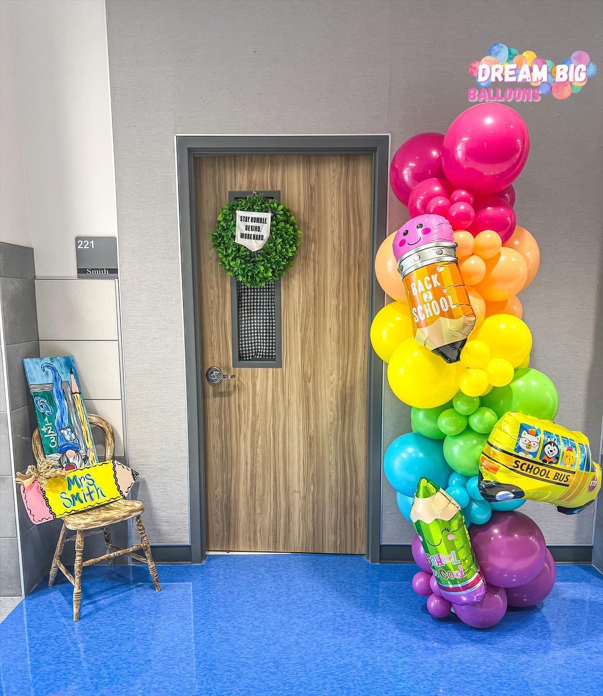 a bunch of balloons are sitting in front of a door in a hallway