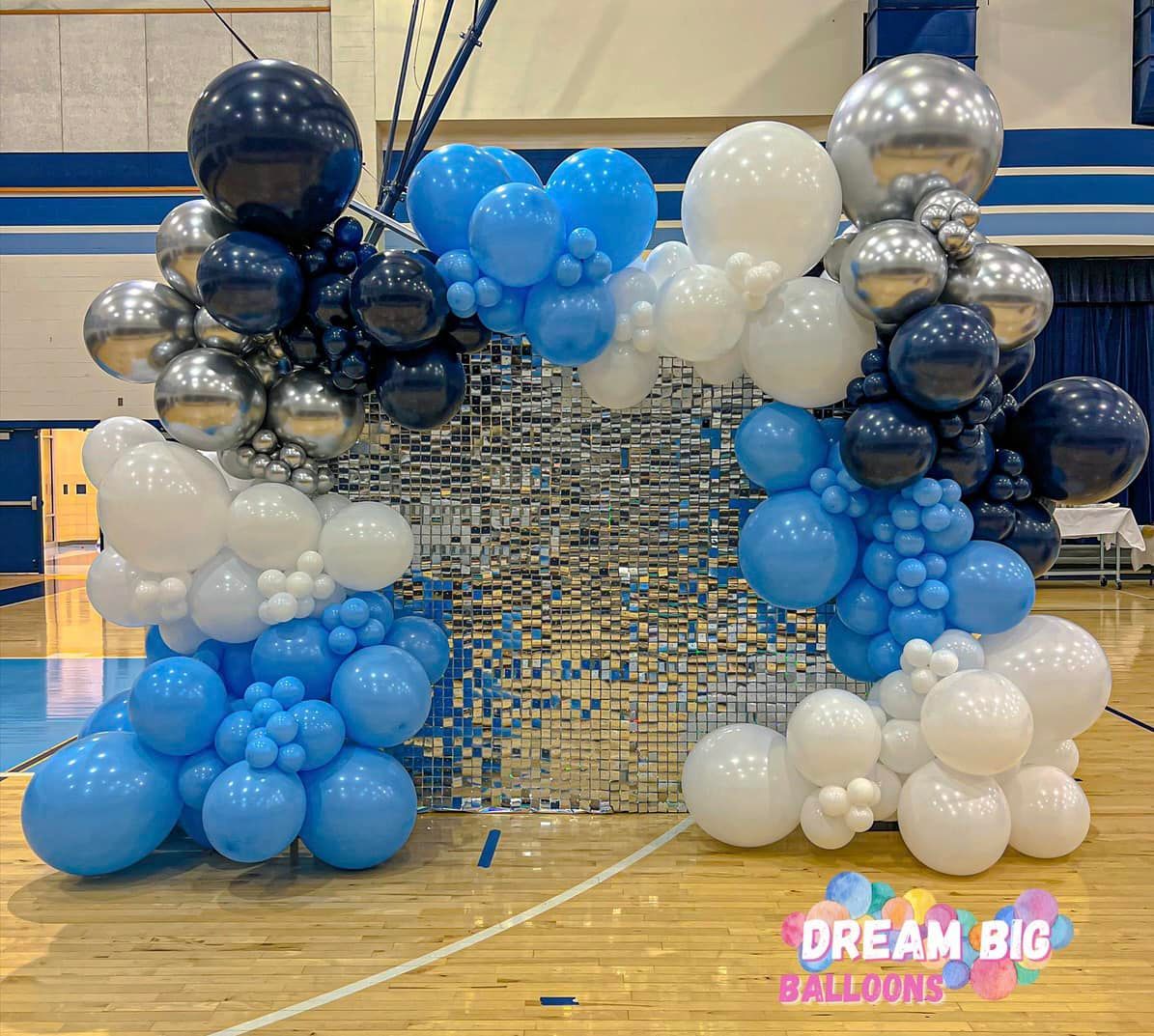 a basketball court covered in blue , white , and silver balloons