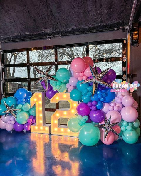 A room filled with balloons and a lighted number 12.