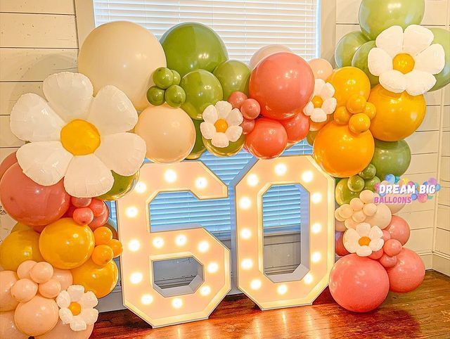 A room decorated with balloons and flowers and a lighted number 60.
