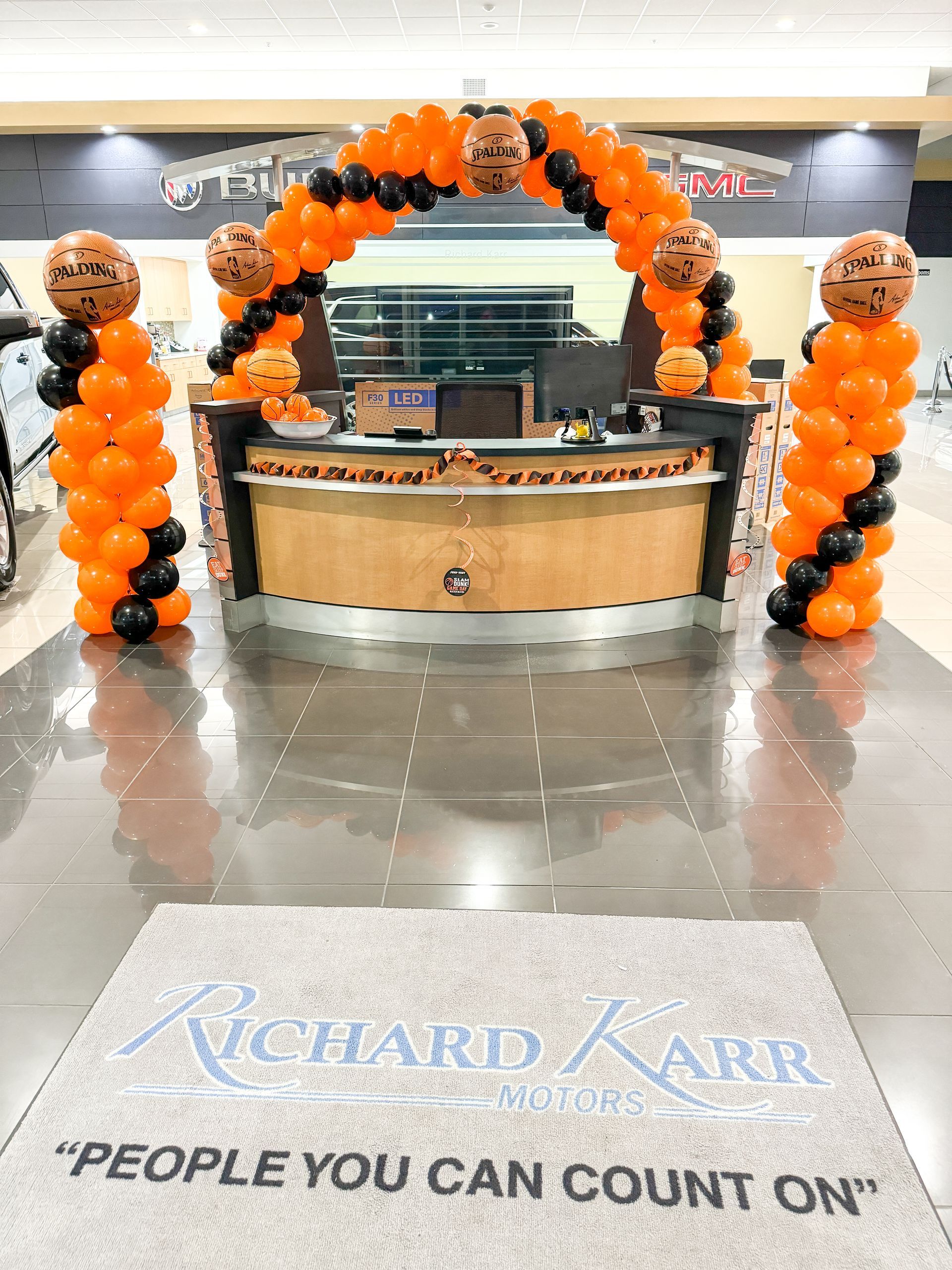 A car dealership is decorated with orange and black basketball balloons.