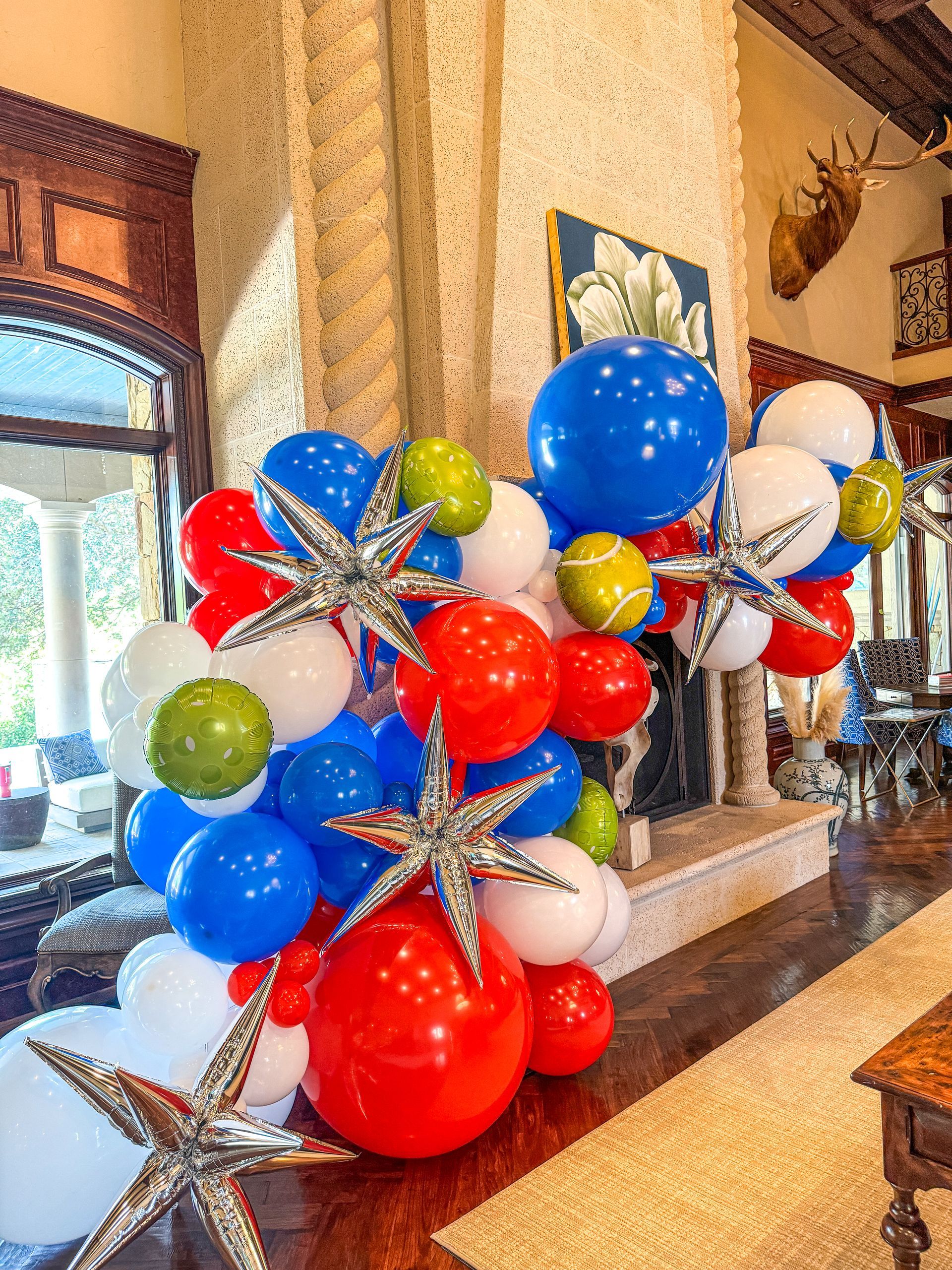A bunch of red , white , and blue balloons in a living room.