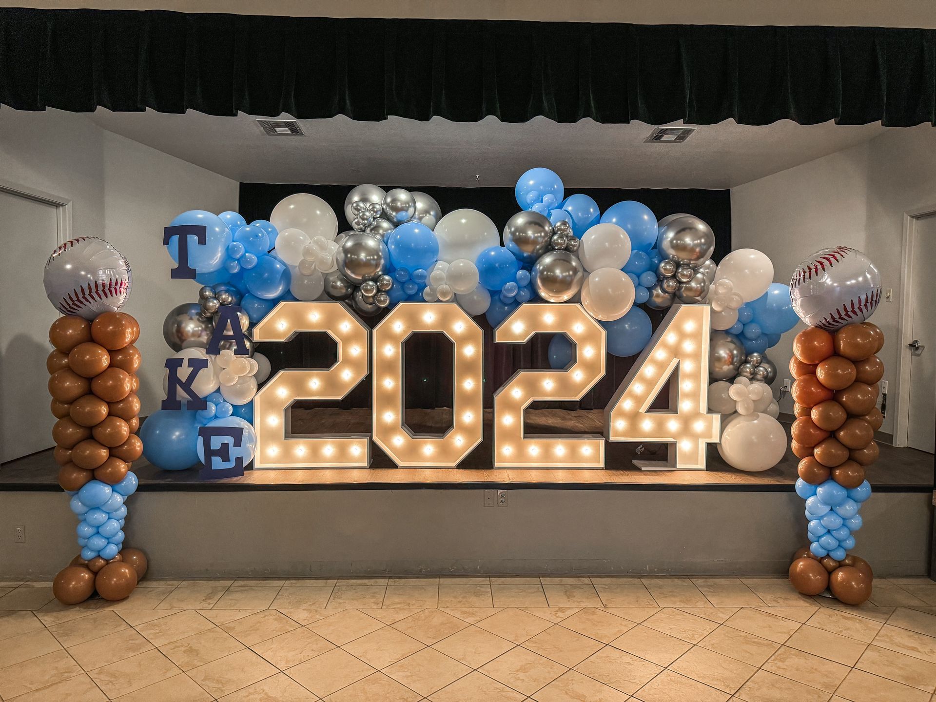 A stage is decorated with balloons and lights for a graduation party.
