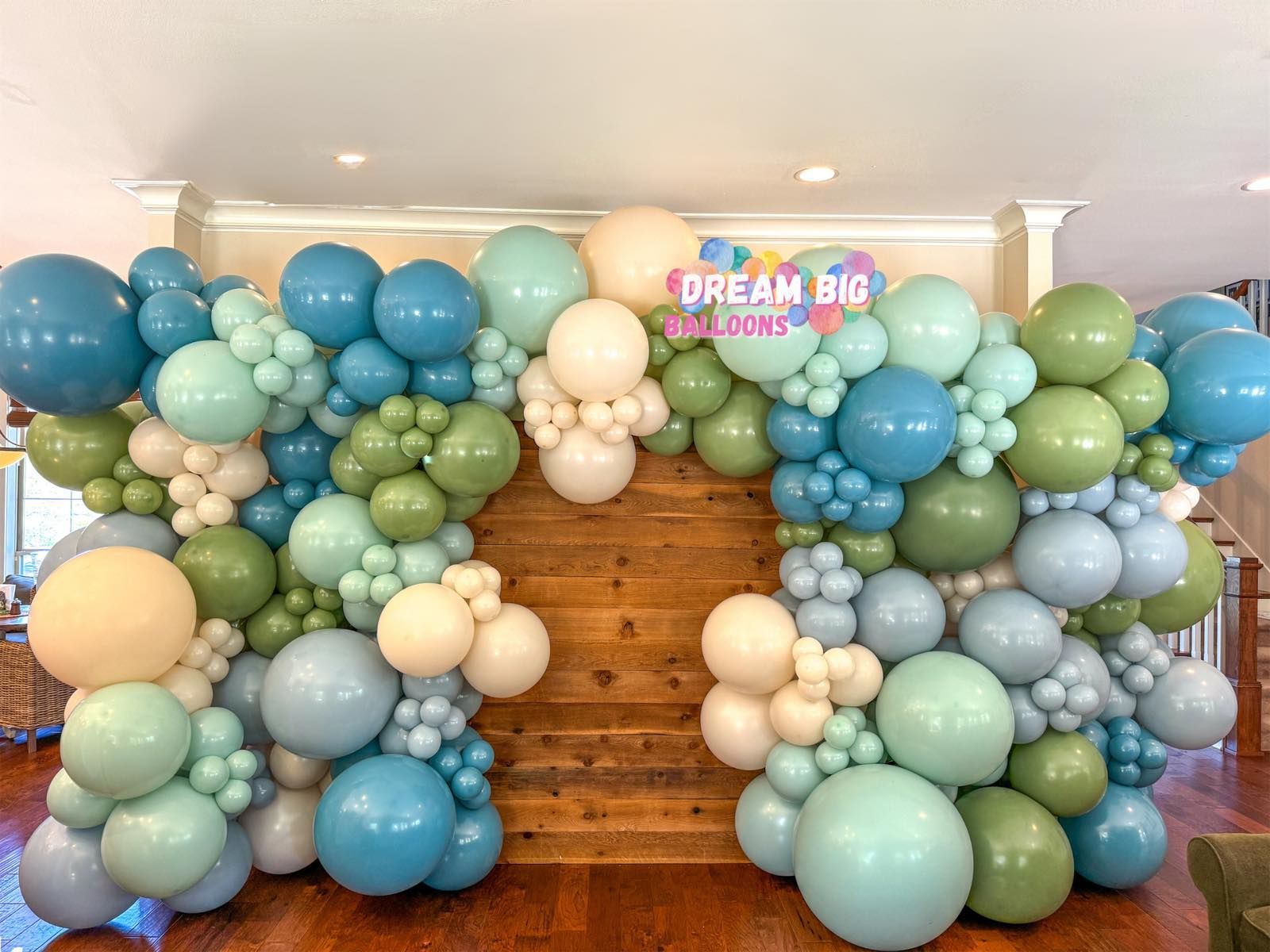 A wooden wall covered in blue and green balloons.