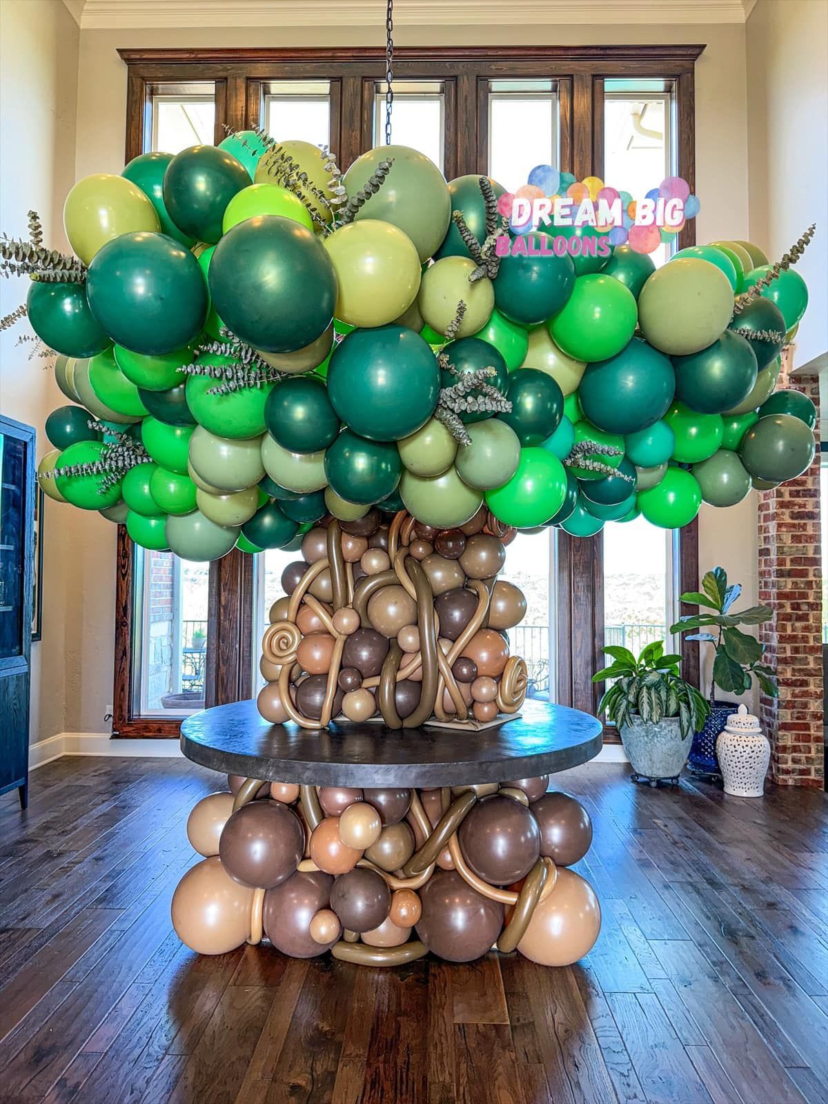 A table covered in green and brown balloons in a living room.