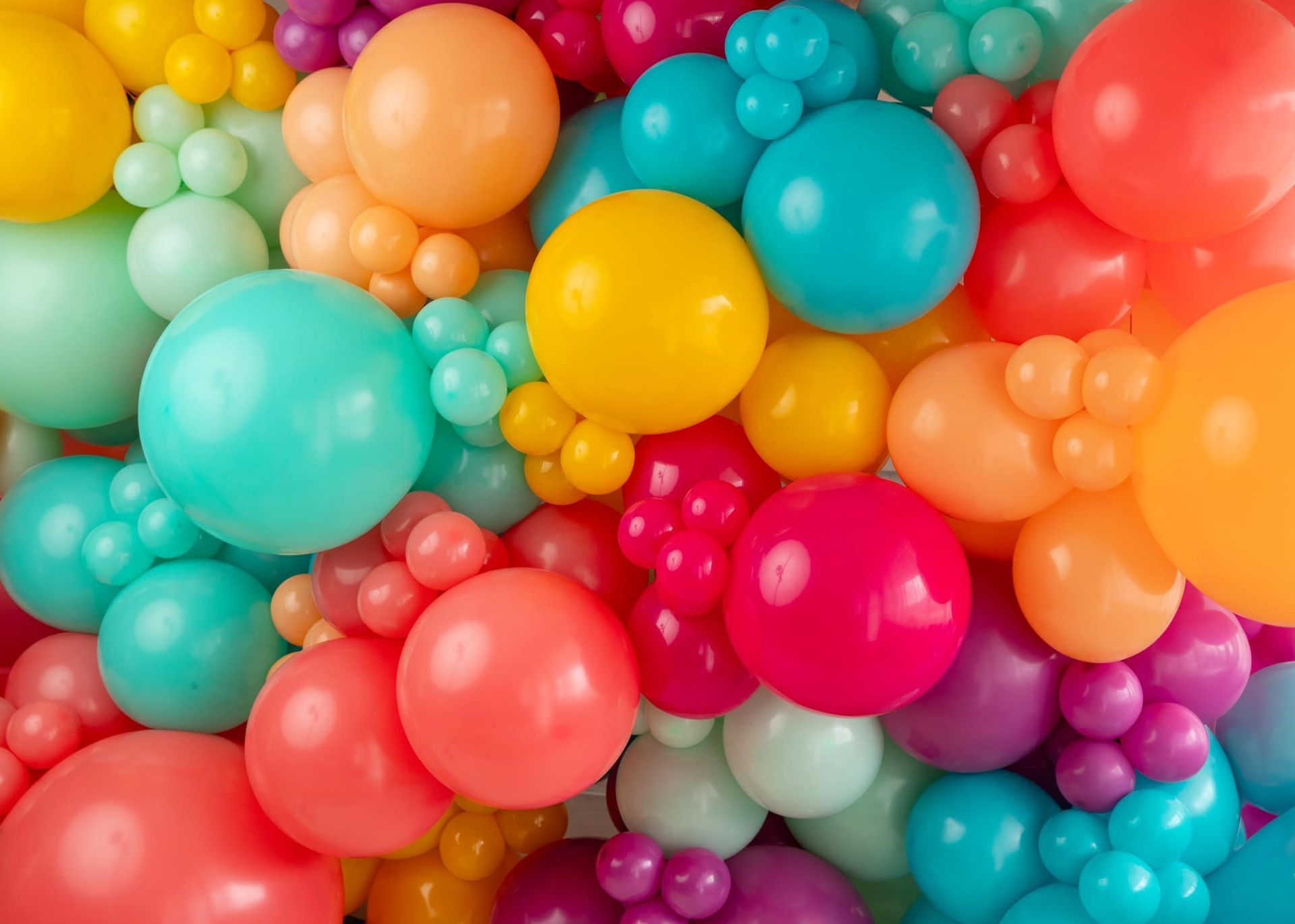 A bunch of colorful balloons are stacked on top of each other.