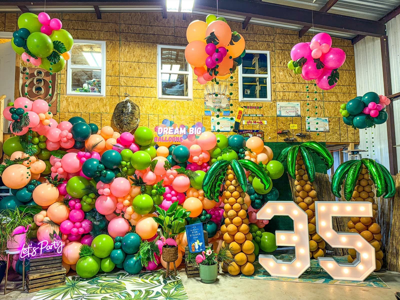 A wall filled with balloons and palm trees for a 35th birthday party.