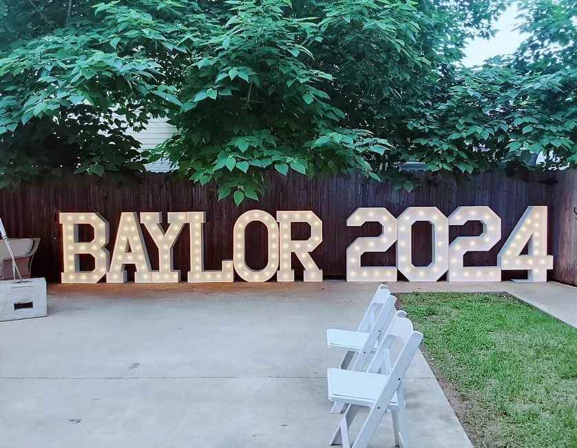 A sign that says baylor 2024 is lit up in front of a fence.