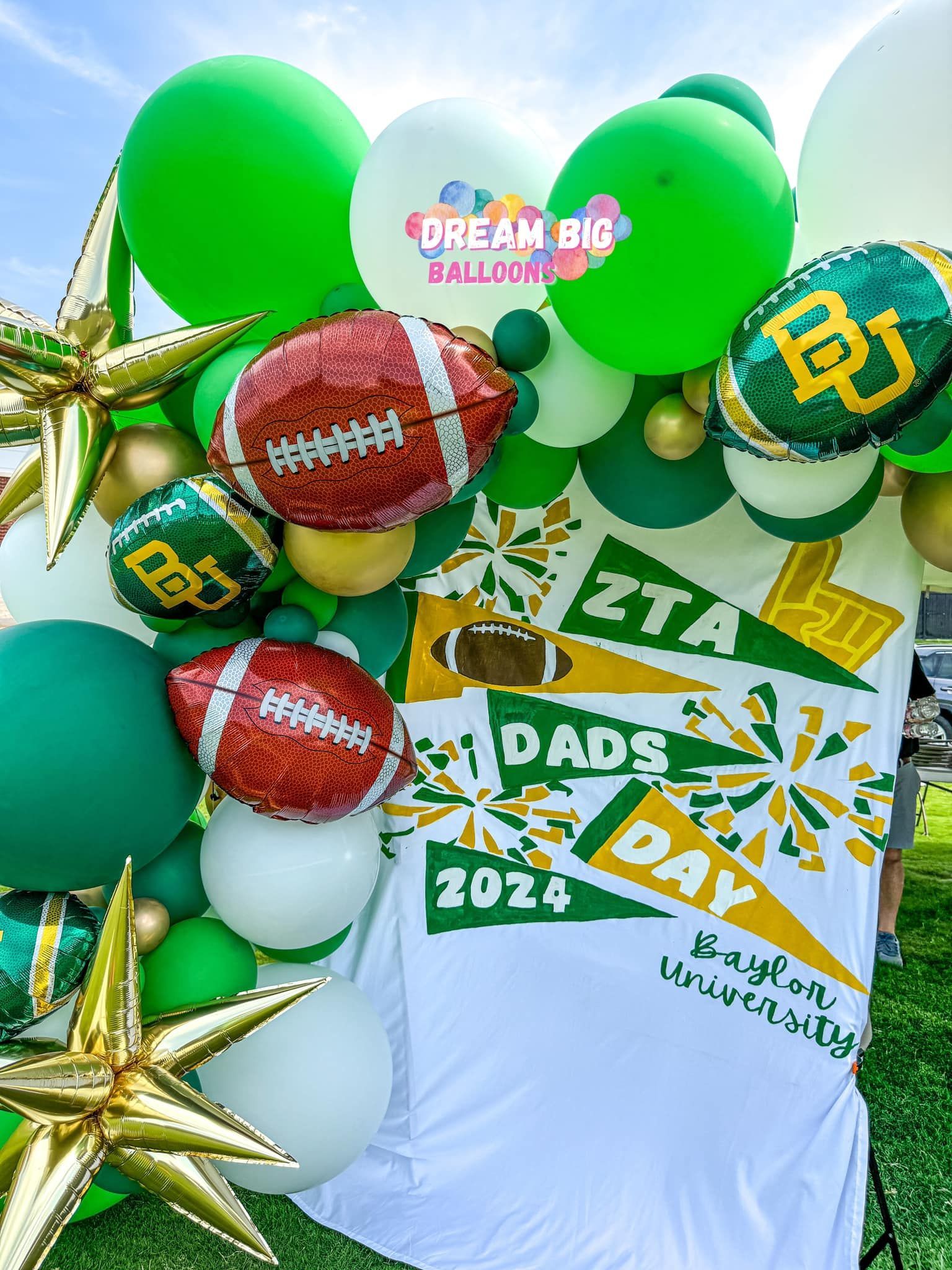 A bunch of green and white balloons are sitting on top of a white cloth.