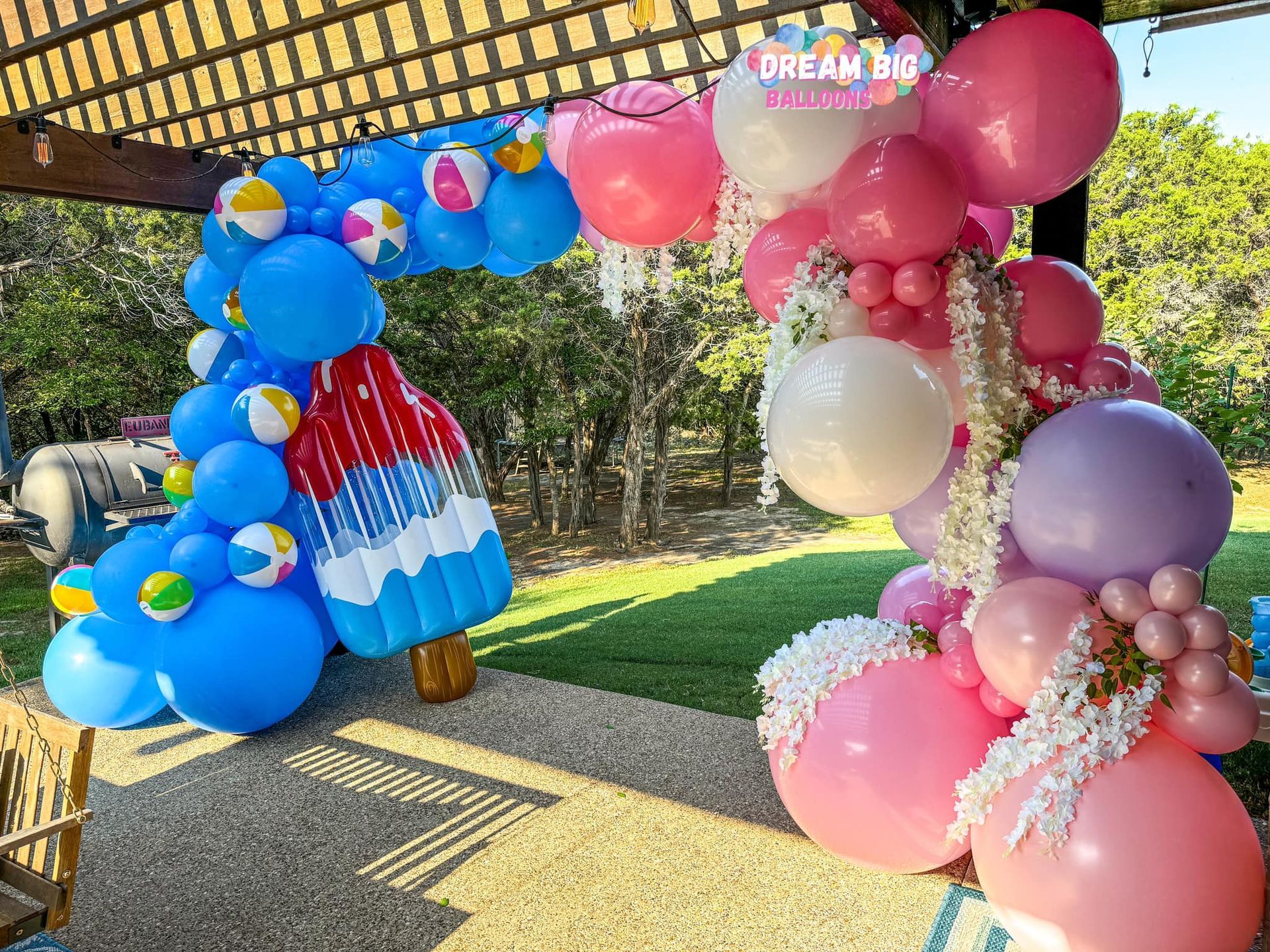 a blue , white , and silver balloon arch is sitting on a porch