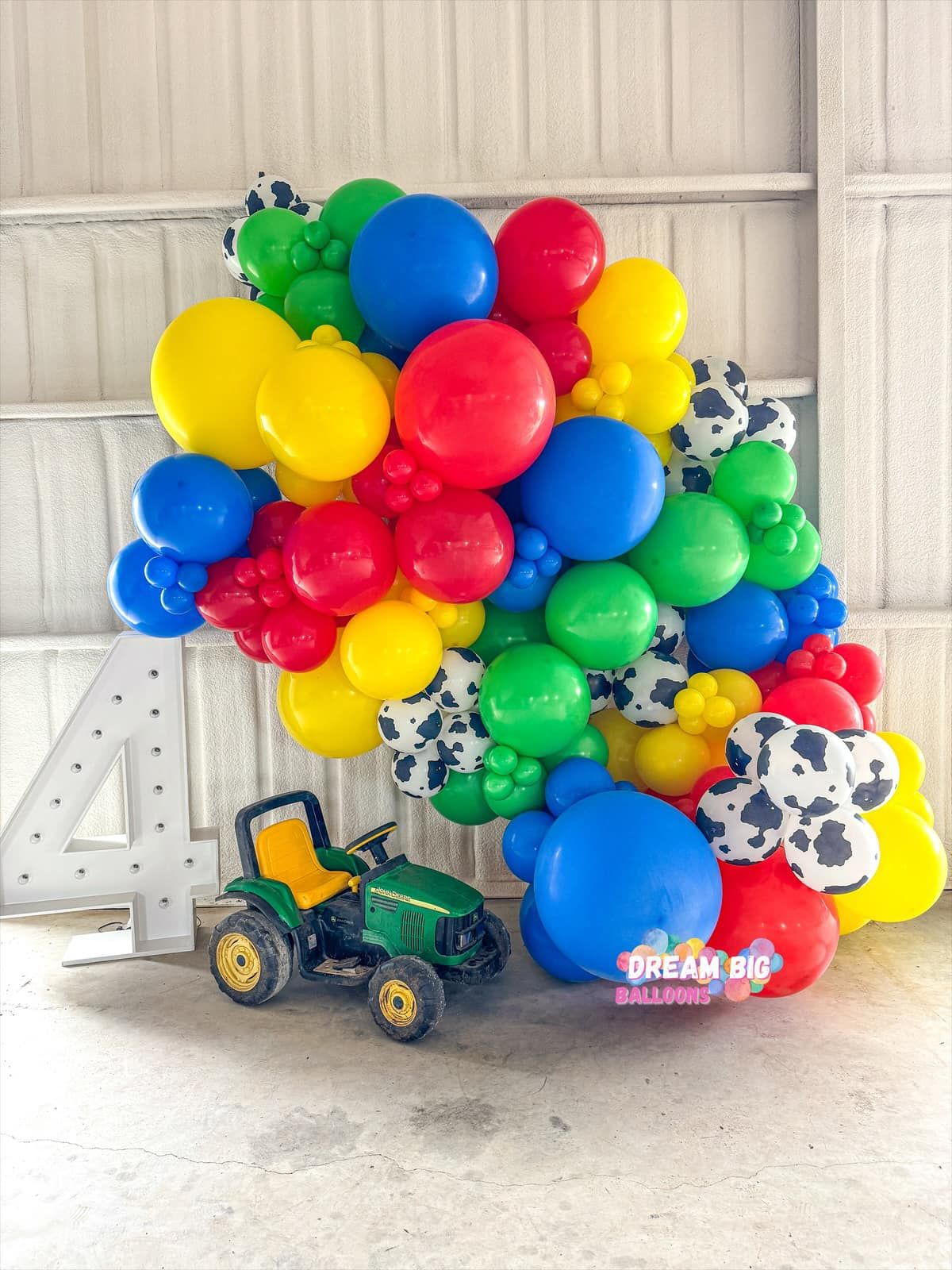 A tractor is sitting next to a bunch of balloons.