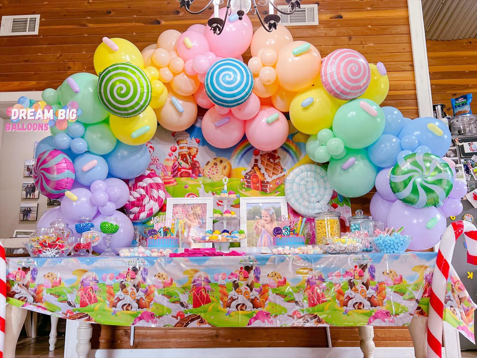 a table decorated with balloons and lollipops for a candy themed birthday party