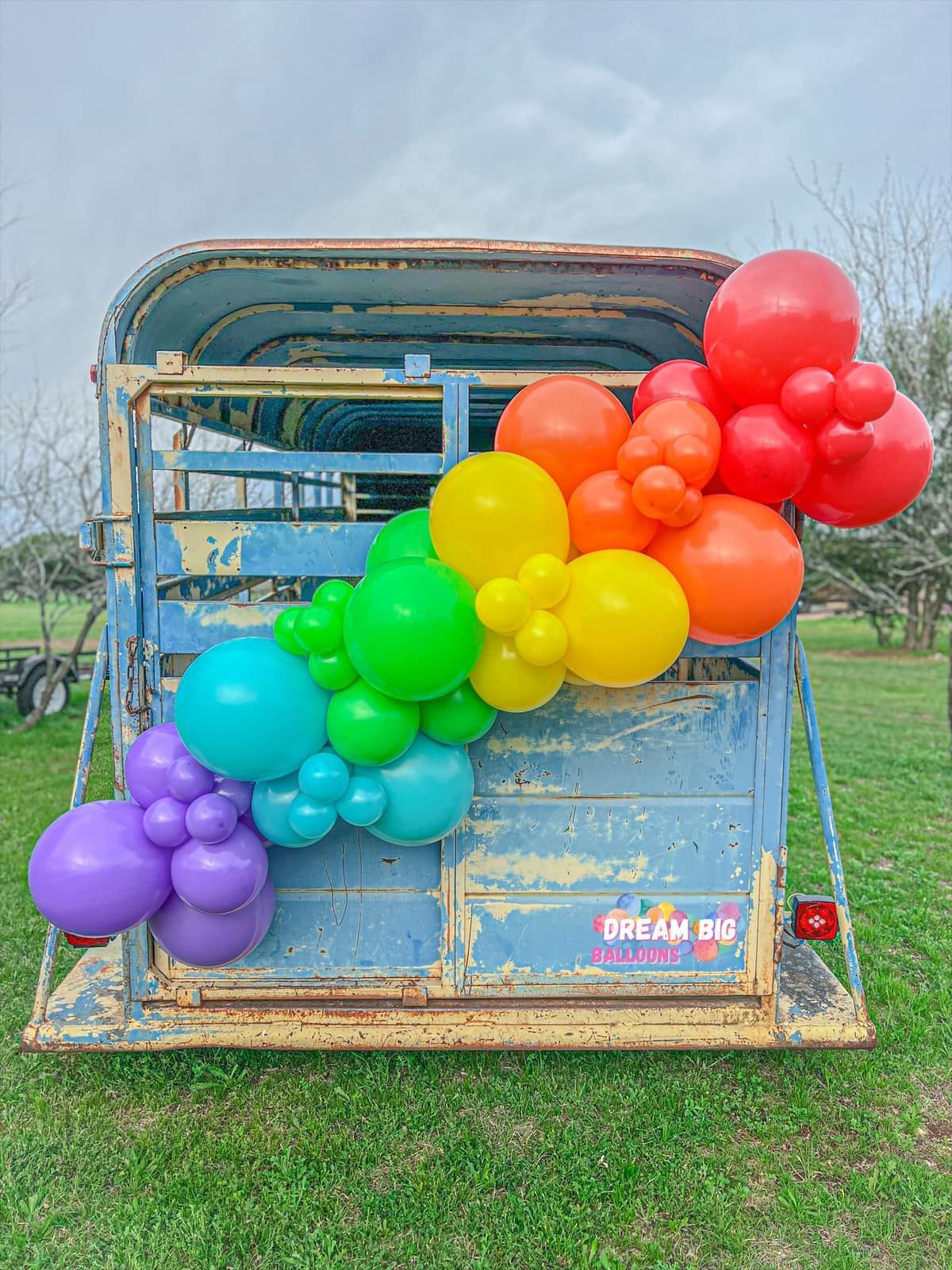 a bunch of balloons are hanging from the back of a horse trailer