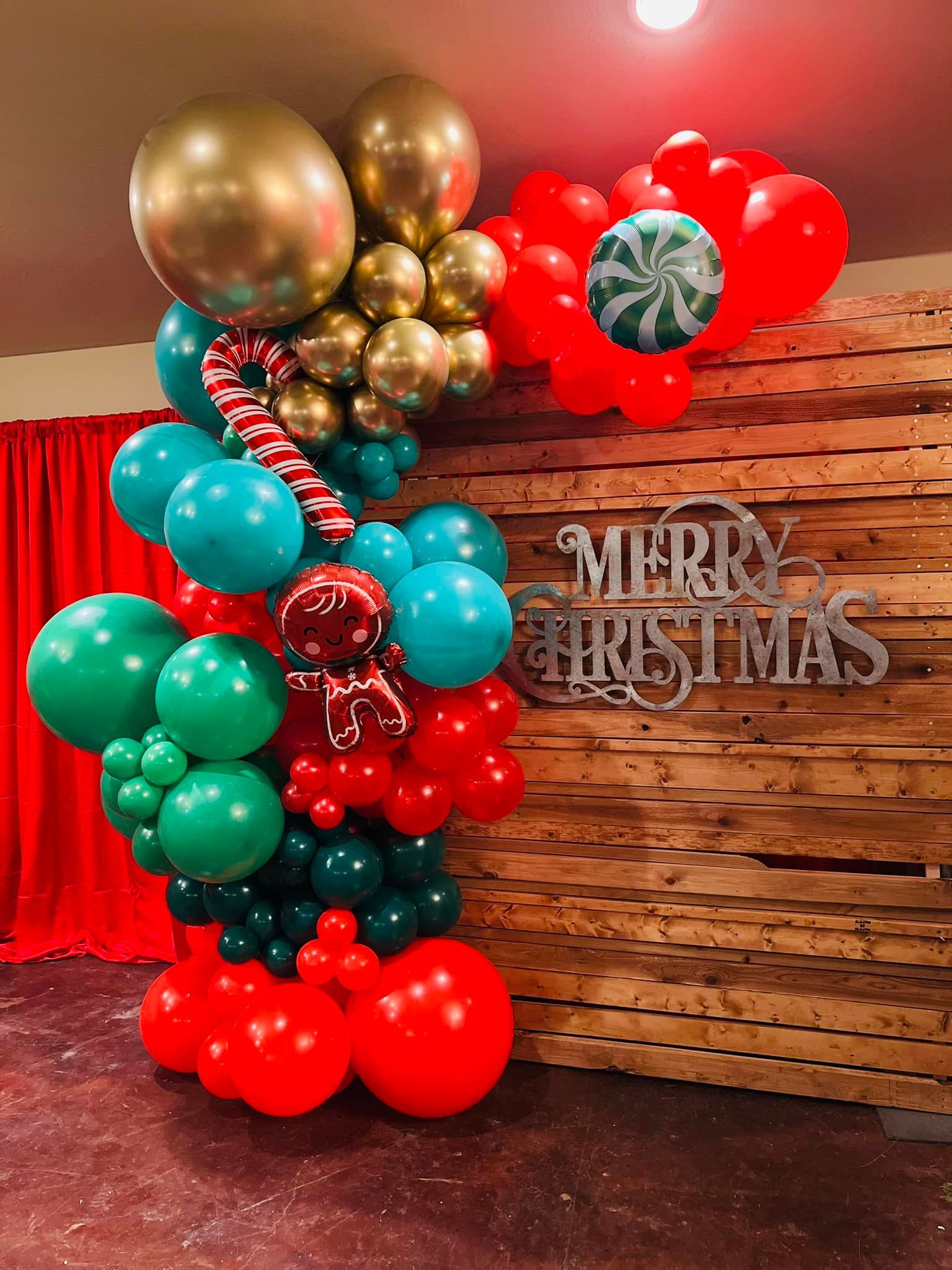 A wooden wall is decorated with balloons and a merry christmas sign.
