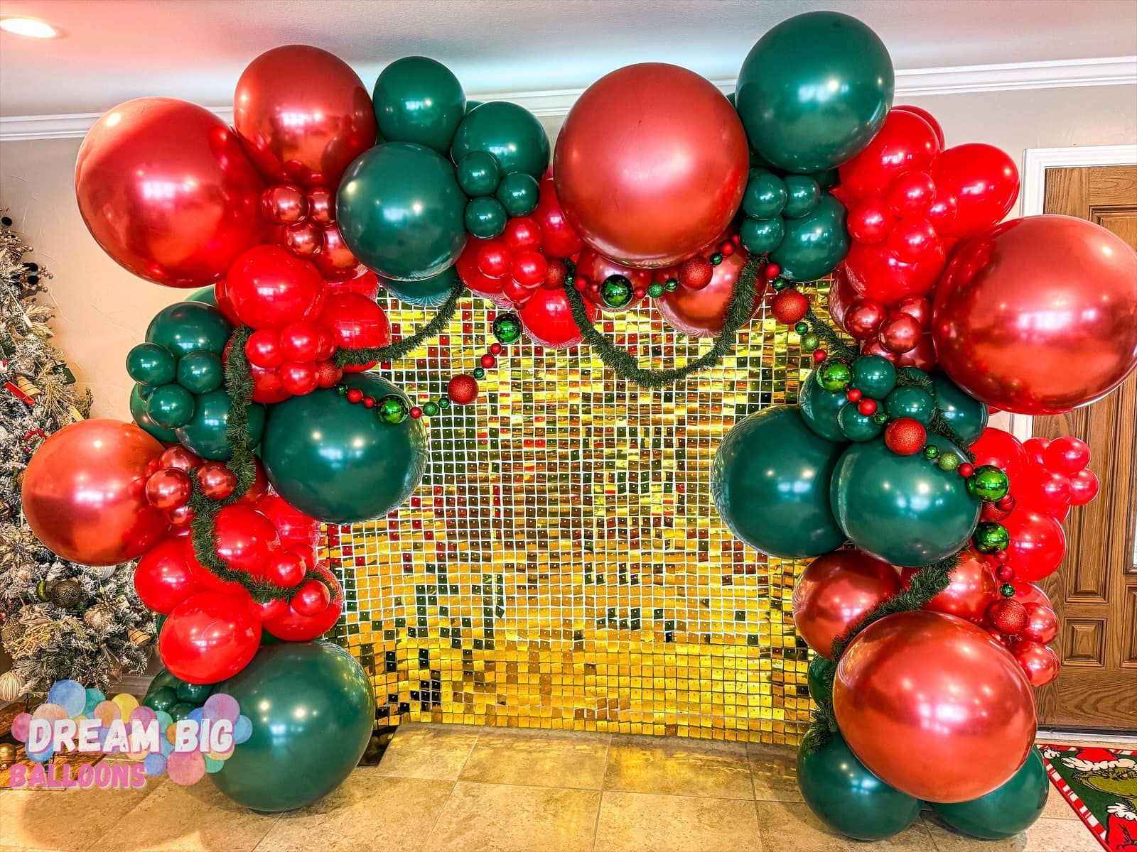 A room filled with red and green balloons and a christmas tree.