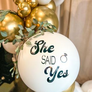 a white balloon with the words she said yes written on it is surrounded by gold balloons